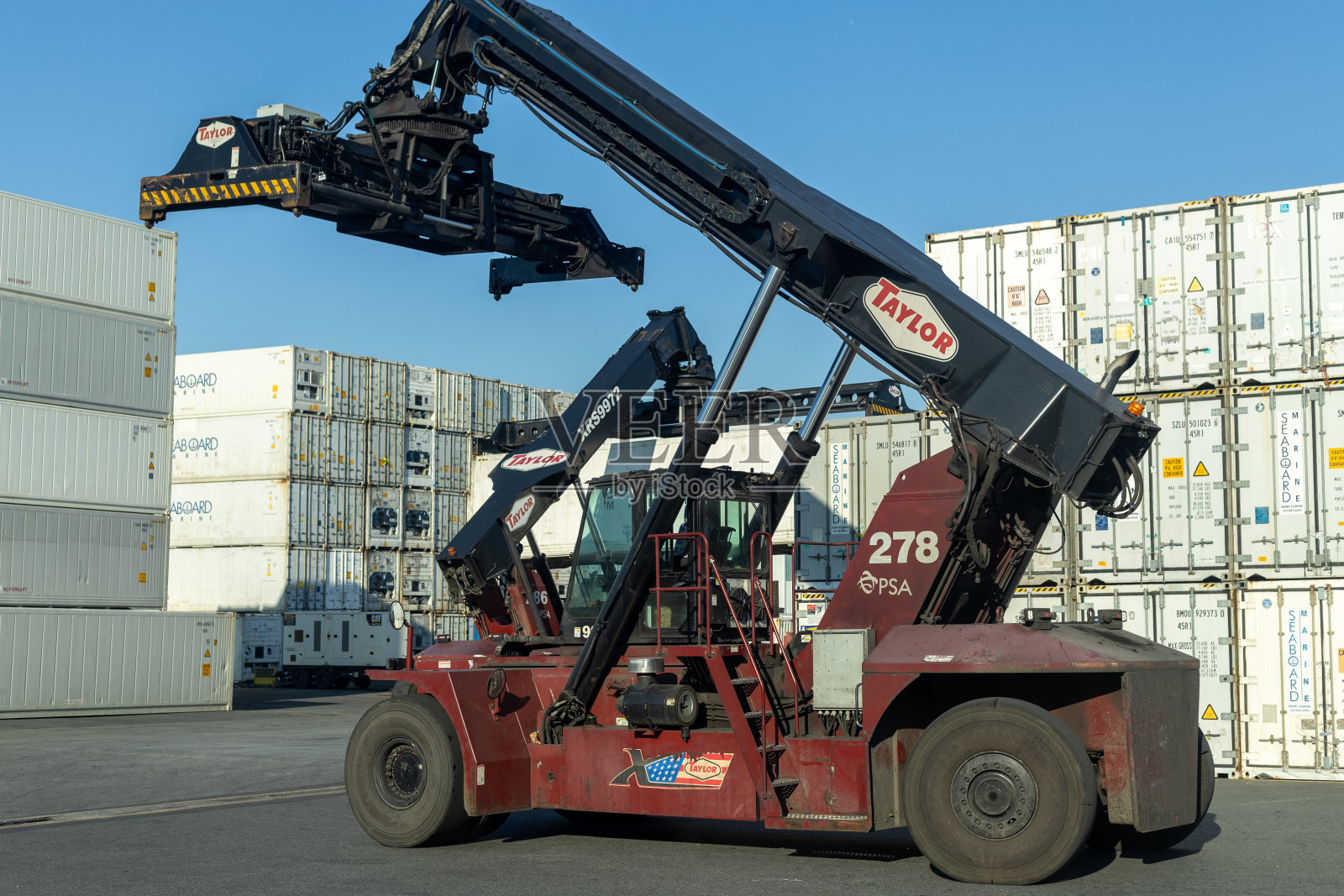 在一个航运码头，在繁忙的工作时间熟练地搬运集装箱。照片摄影图片