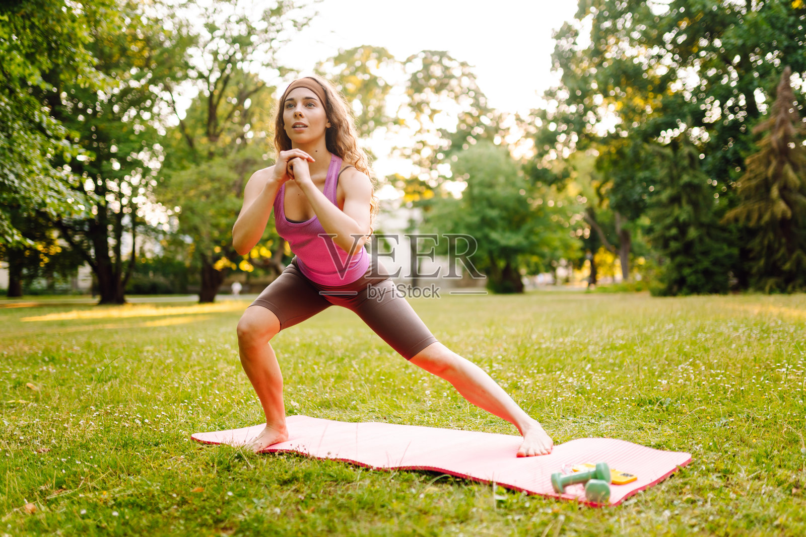 穿着运动服的年轻女子在公园的健身垫上伸展身体，做瑜伽。照片摄影图片