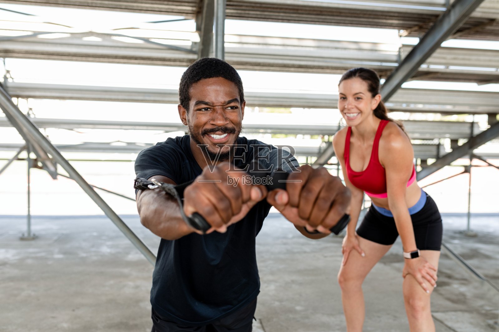 一名男子在他的健身教练旁边使用电缆机照片摄影图片