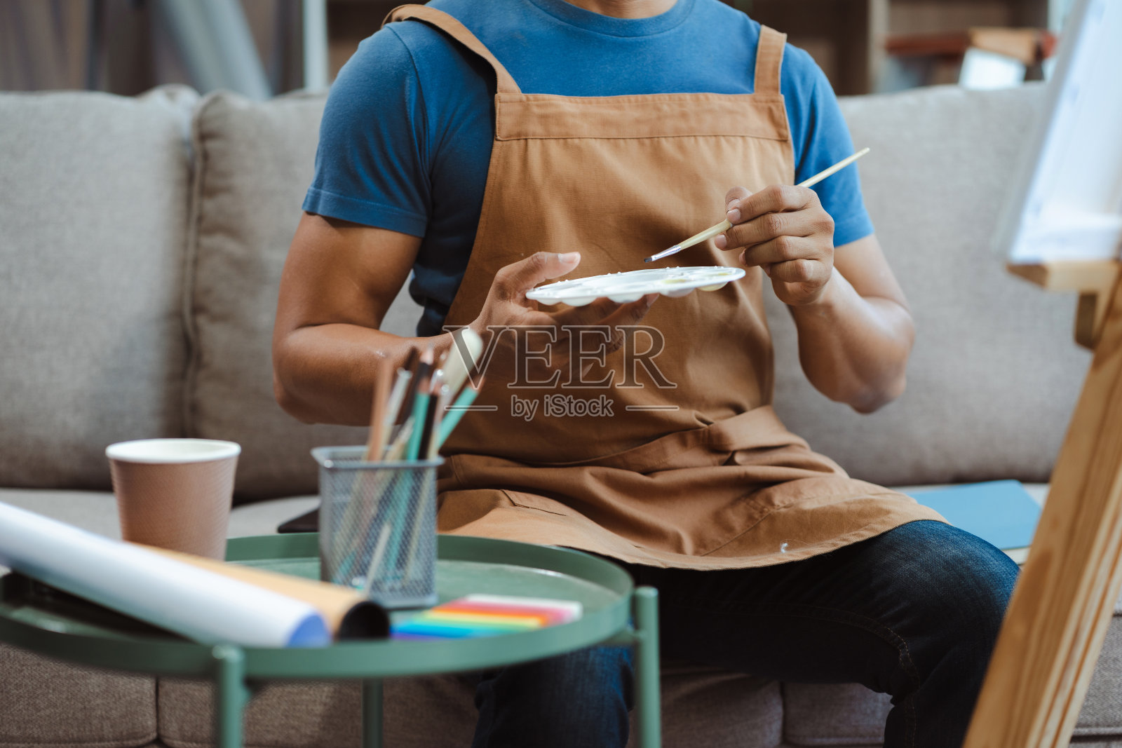 在艺术工作室里创作的画家。有艺术天分的年轻人正在画一幅新画。照片摄影图片