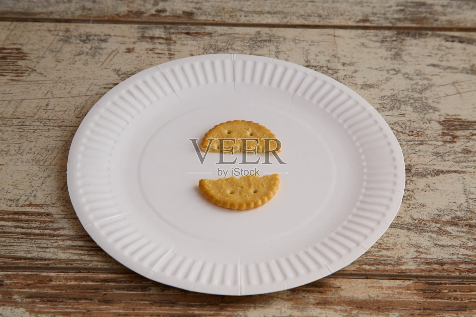 一个碎饼干放在木制背景的一次性盘子里，特写，不断上涨的食品价格，严格的饮食，卡路里限制，贫乏的饮食照片摄影图片