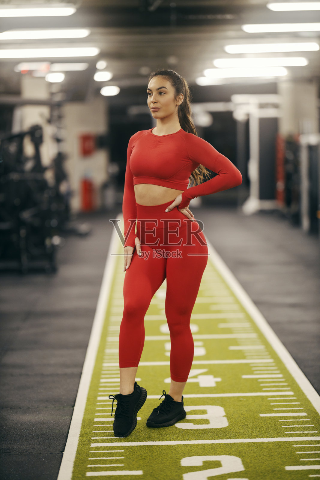 一个身材匀称的女运动员站在健身房的肖像。照片摄影图片