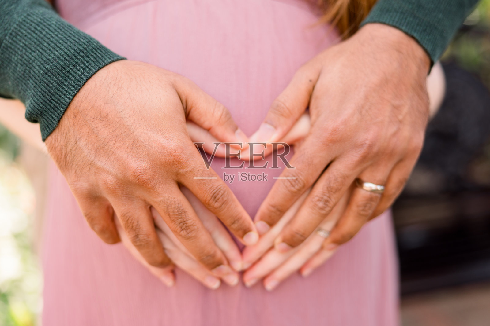 一位印度父亲在他高加索妻子的肚子上画了一个心形图案照片摄影图片