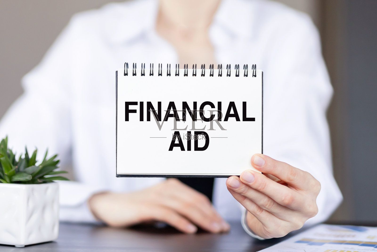 在办公室里生意人手里的纸质记事本上记录财务援助。经营理念照片摄影图片