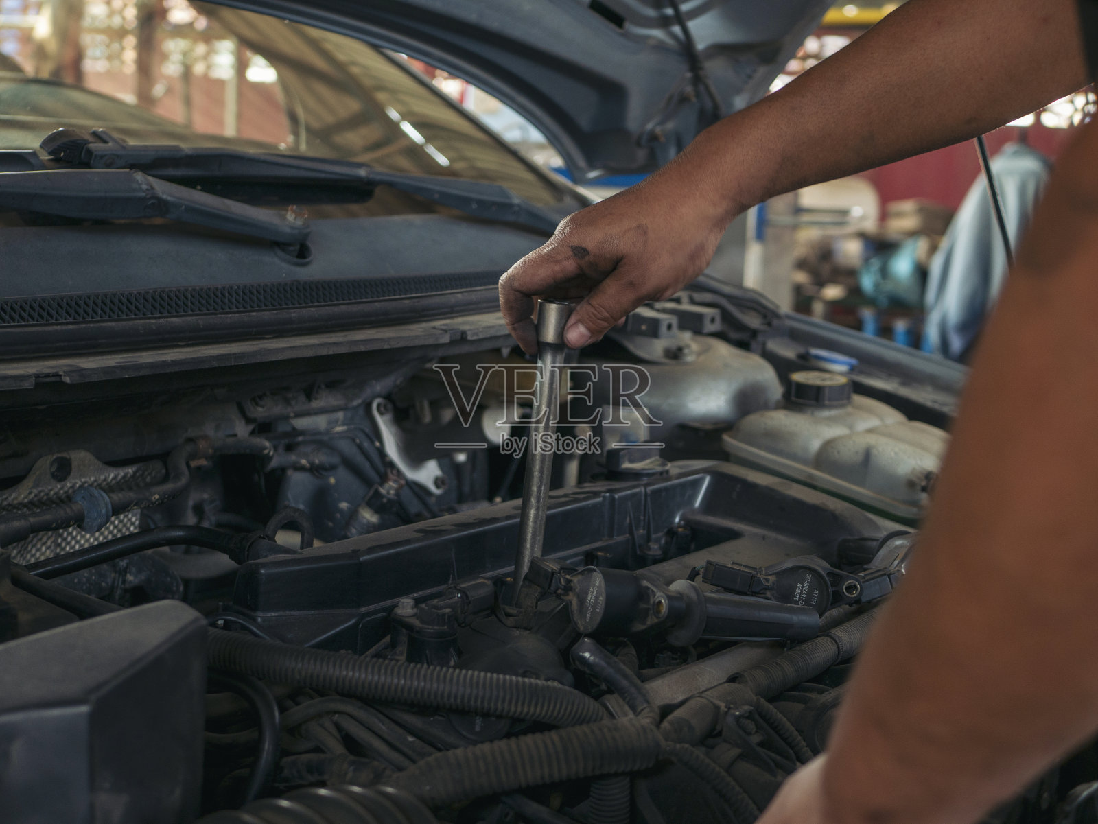 近景:工人修理汽车机械车辆机械服务。修车技工手修汽车修理店。打开汽车引擎盖检查汽车。汽车维修工程师。照片摄影图片