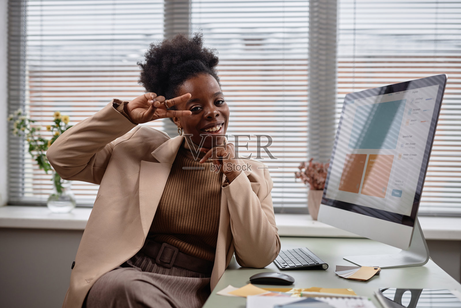 年轻可爱的女商人在工作场所表现出v字手势照片摄影图片