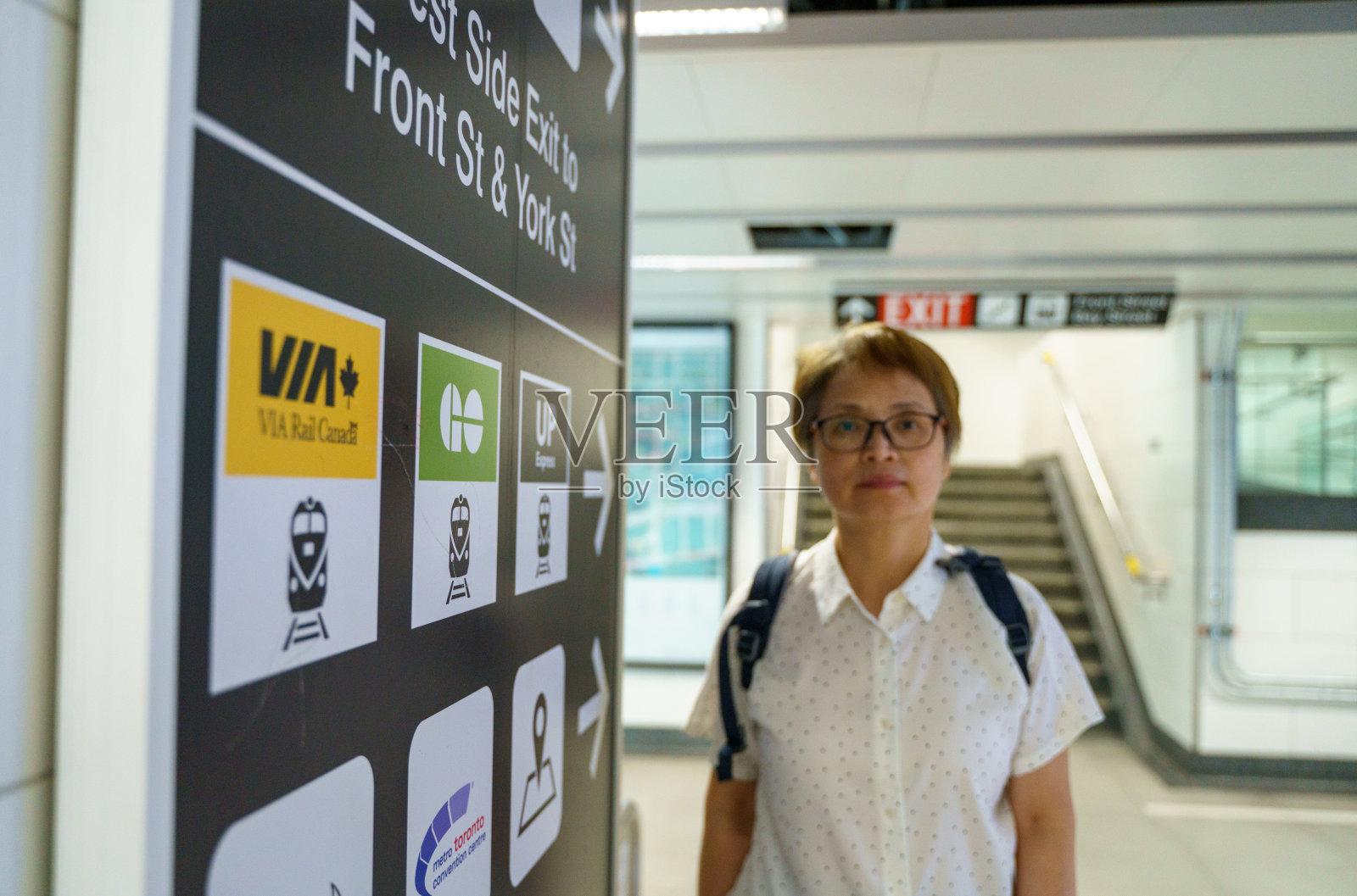 一位年长的女游客在多伦多联合车站内查看车站标志。照片摄影图片