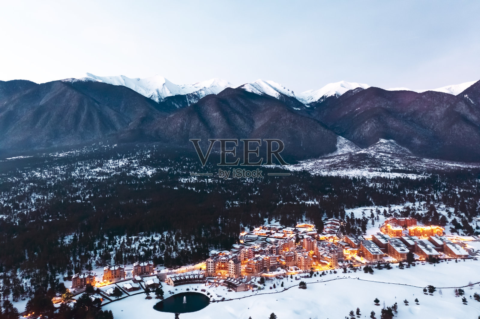 鸟瞰皮林高尔夫俱乐部滑雪胜地。冬季，在日落的背景下，山脚下的高尔夫球场被橙色的灯光照亮。无人机。旅行的概念。旅游照片摄影图片