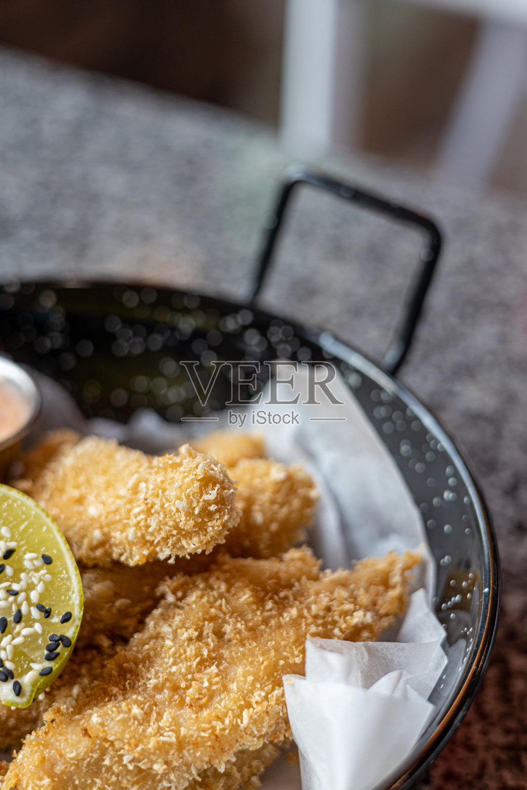 金黄的油炸鸡块。多汁的鸡肉块裹在美味的面糊里，用Panko炸脆，裹着酱汁(特写)放在桌上的盘子里。照片摄影图片