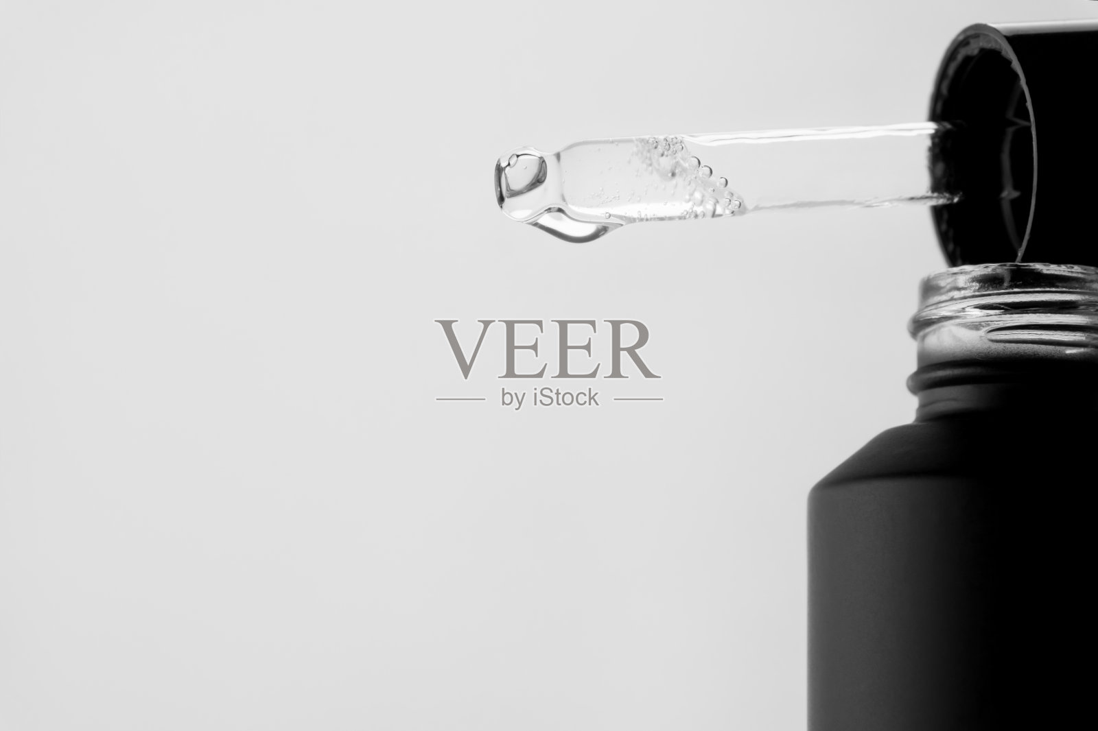 一滴化妆品芳香油从移液管中滴下。前视图。照片摄影图片