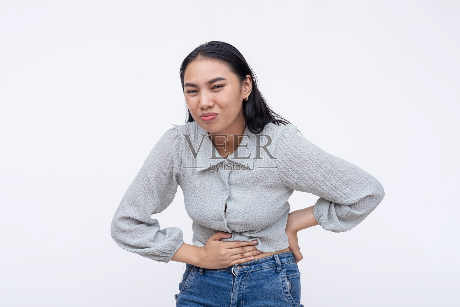 亚洲妇女感到不适，抱着她的腹部疼痛与不安的表情，孤立在一个白色的背景。照片摄影图片