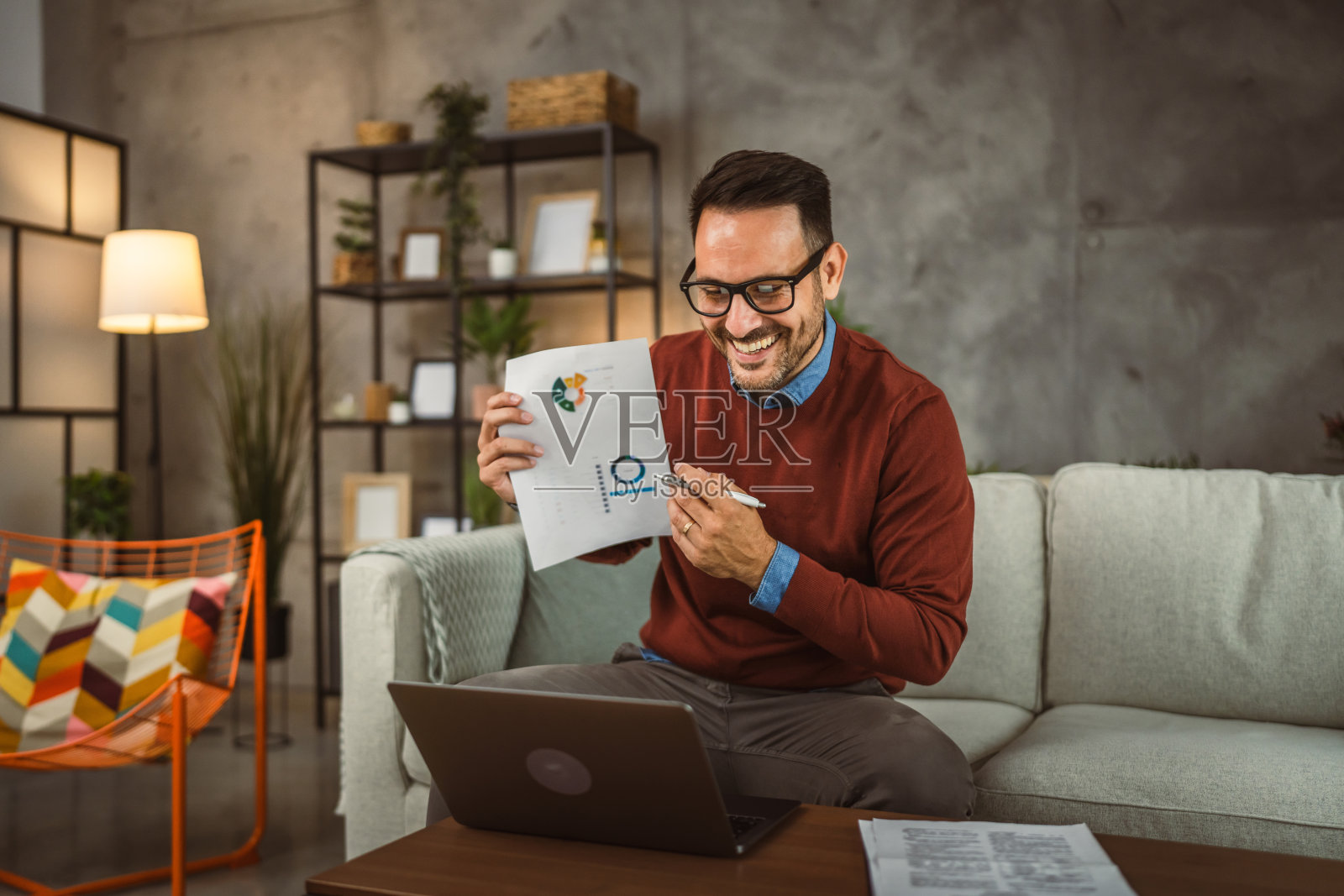 男人在家工作，在笔记本电脑上进行视频通话，分享图表照片摄影图片
