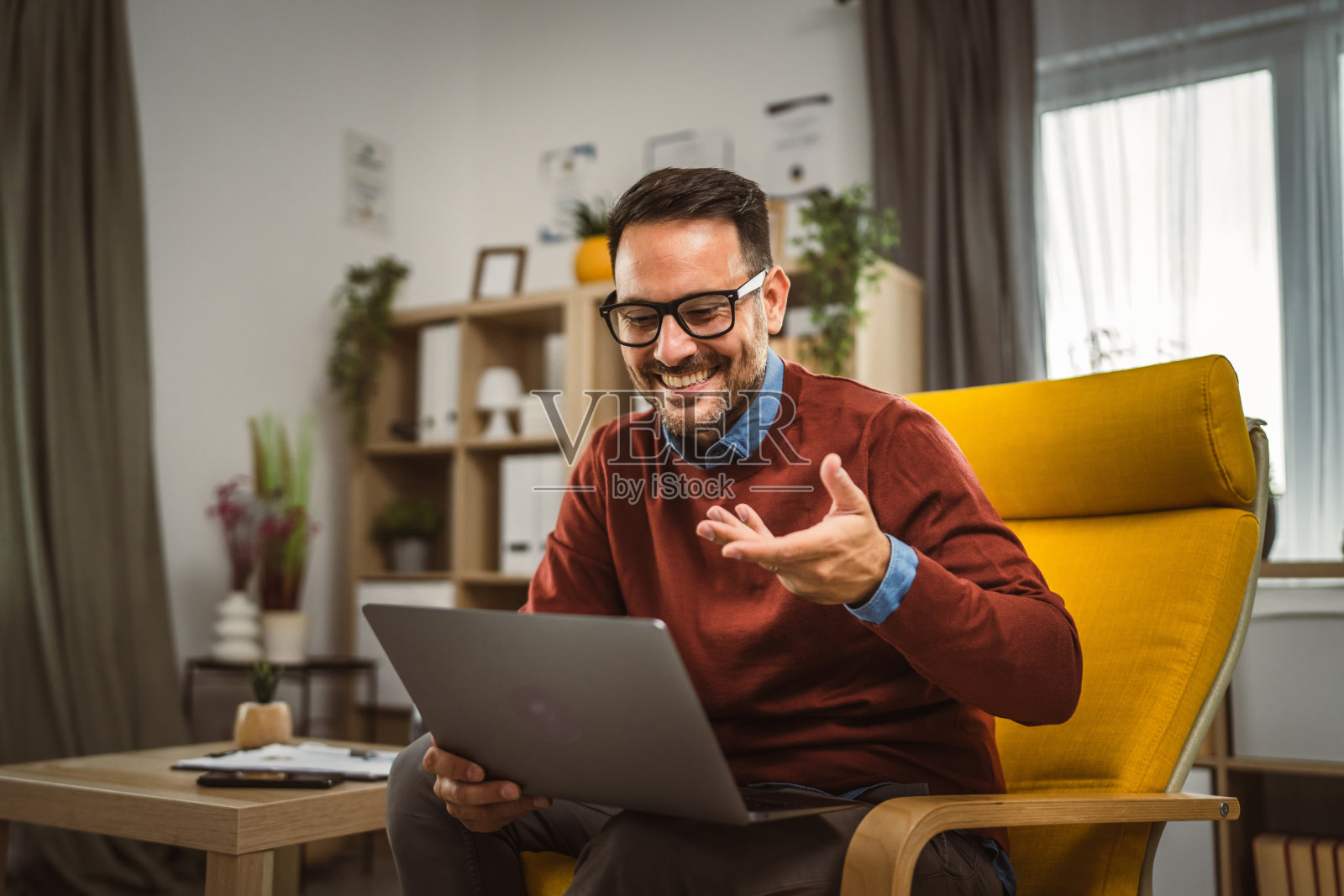 男人在家工作，在笔记本电脑上进行视频通话，分享图表照片摄影图片