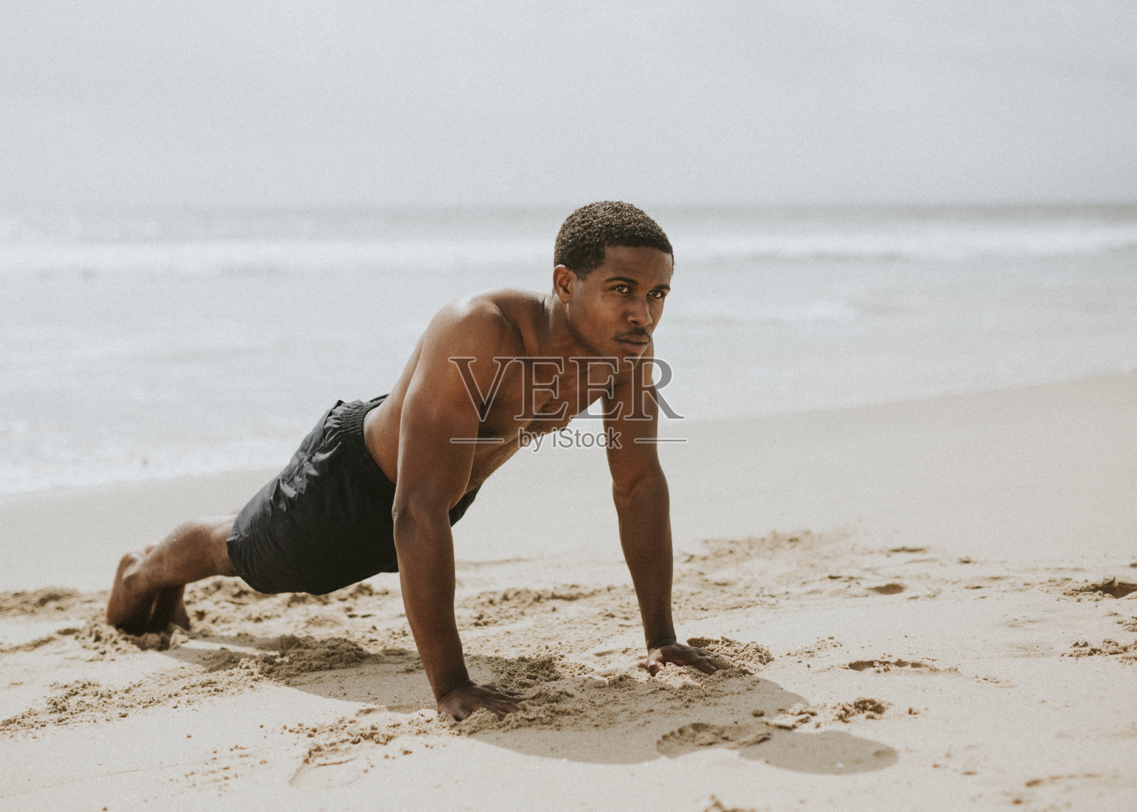 肌肉发达的黑人在海滩上做俯卧撑照片摄影图片
