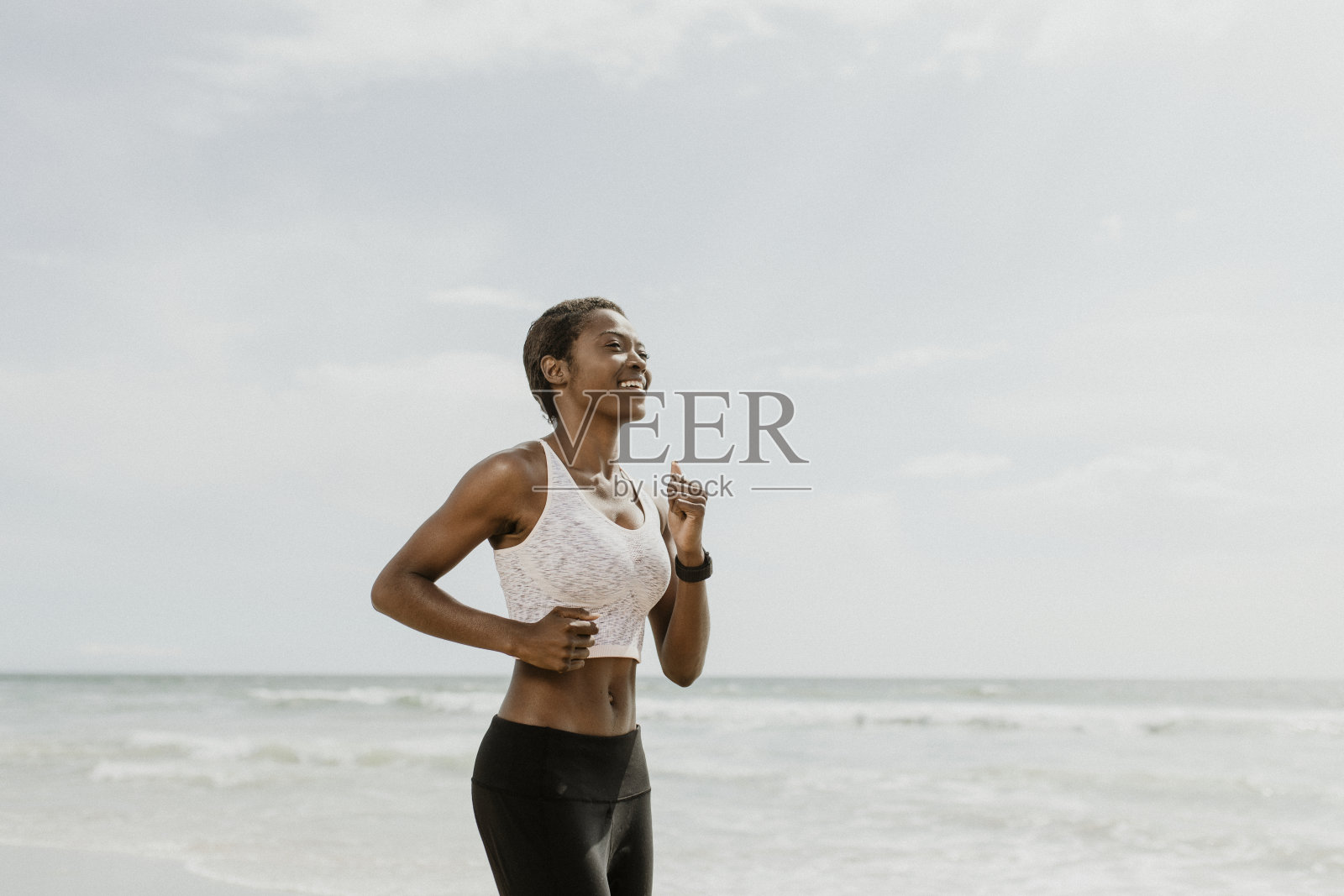 快乐的黑人妇女在沙滩上慢跑照片摄影图片