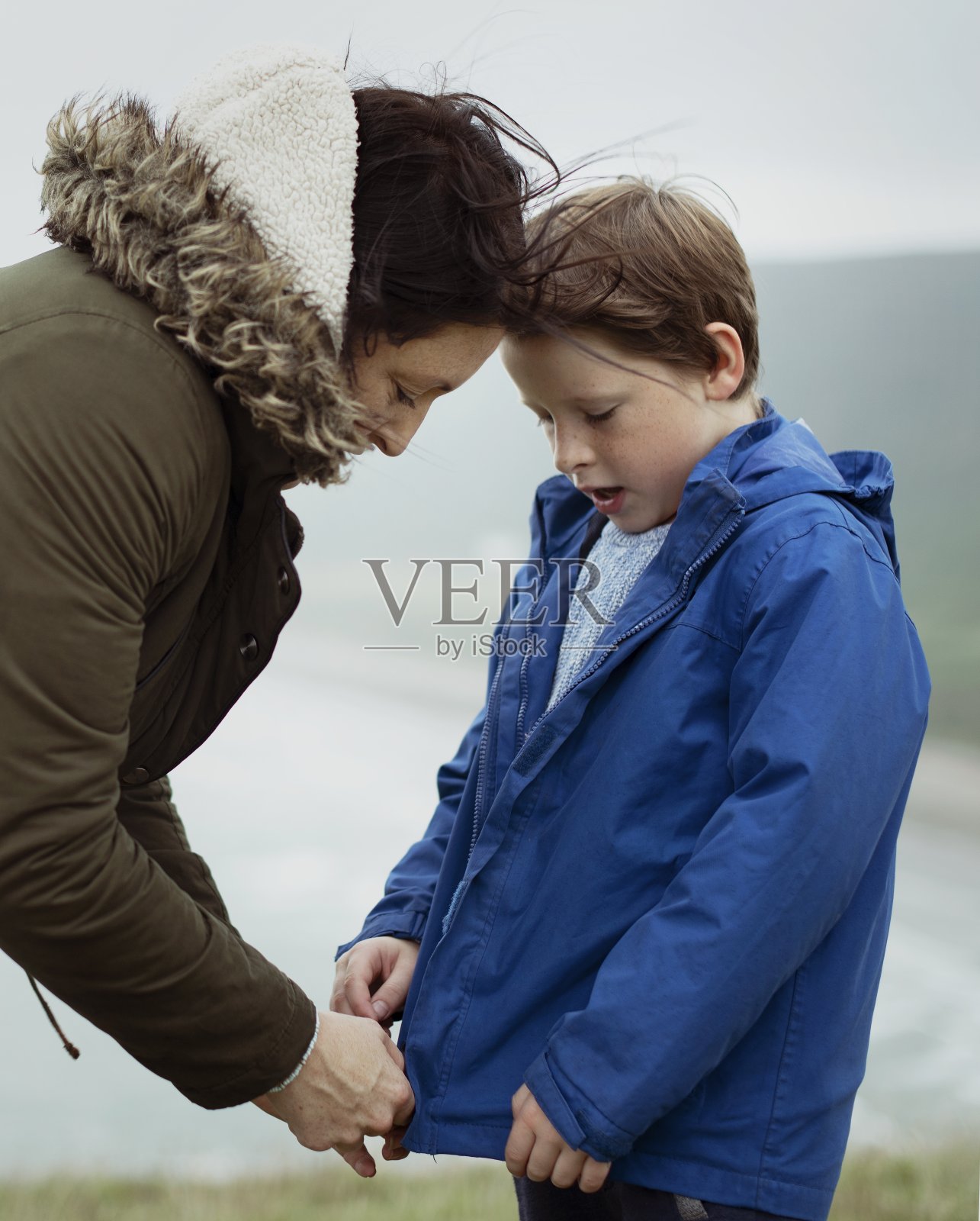 母亲在帮儿子拉夹克的拉链照片摄影图片