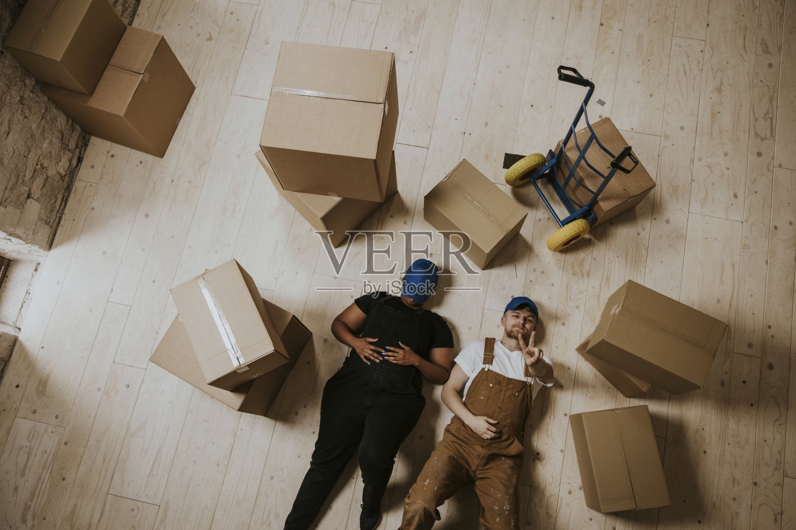 快乐的搬家服务工作者躺在地板上照片摄影图片