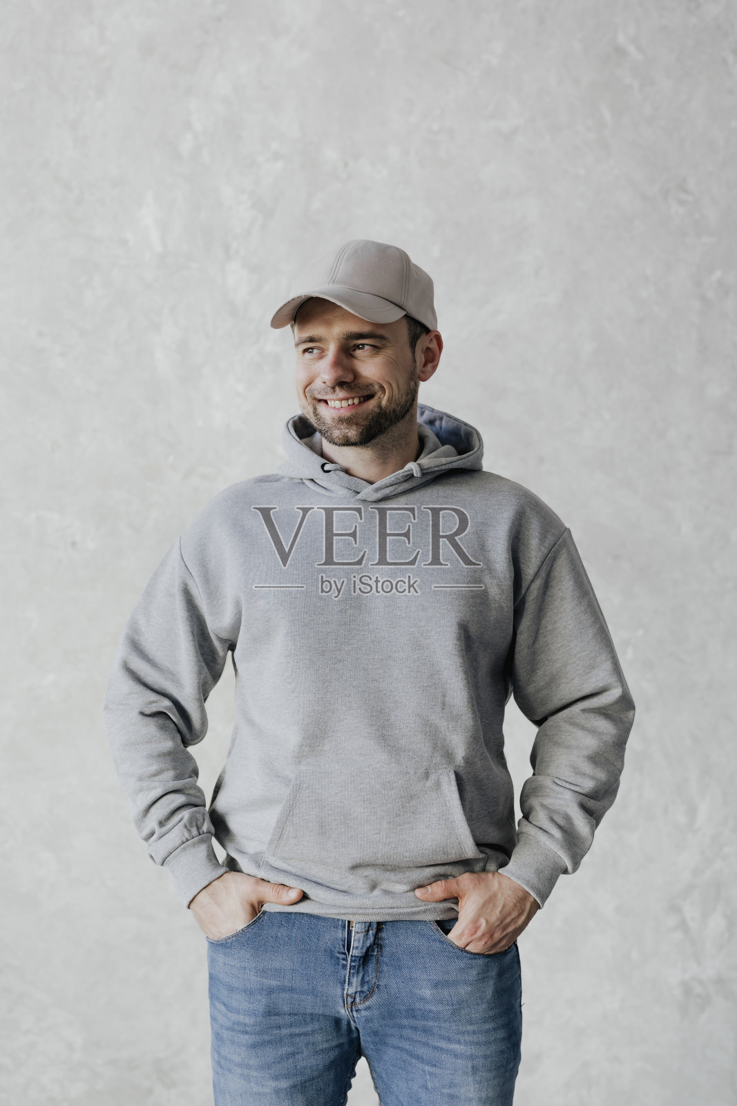 戴着帽子，穿着灰色连帽衫的快乐男人照片摄影图片