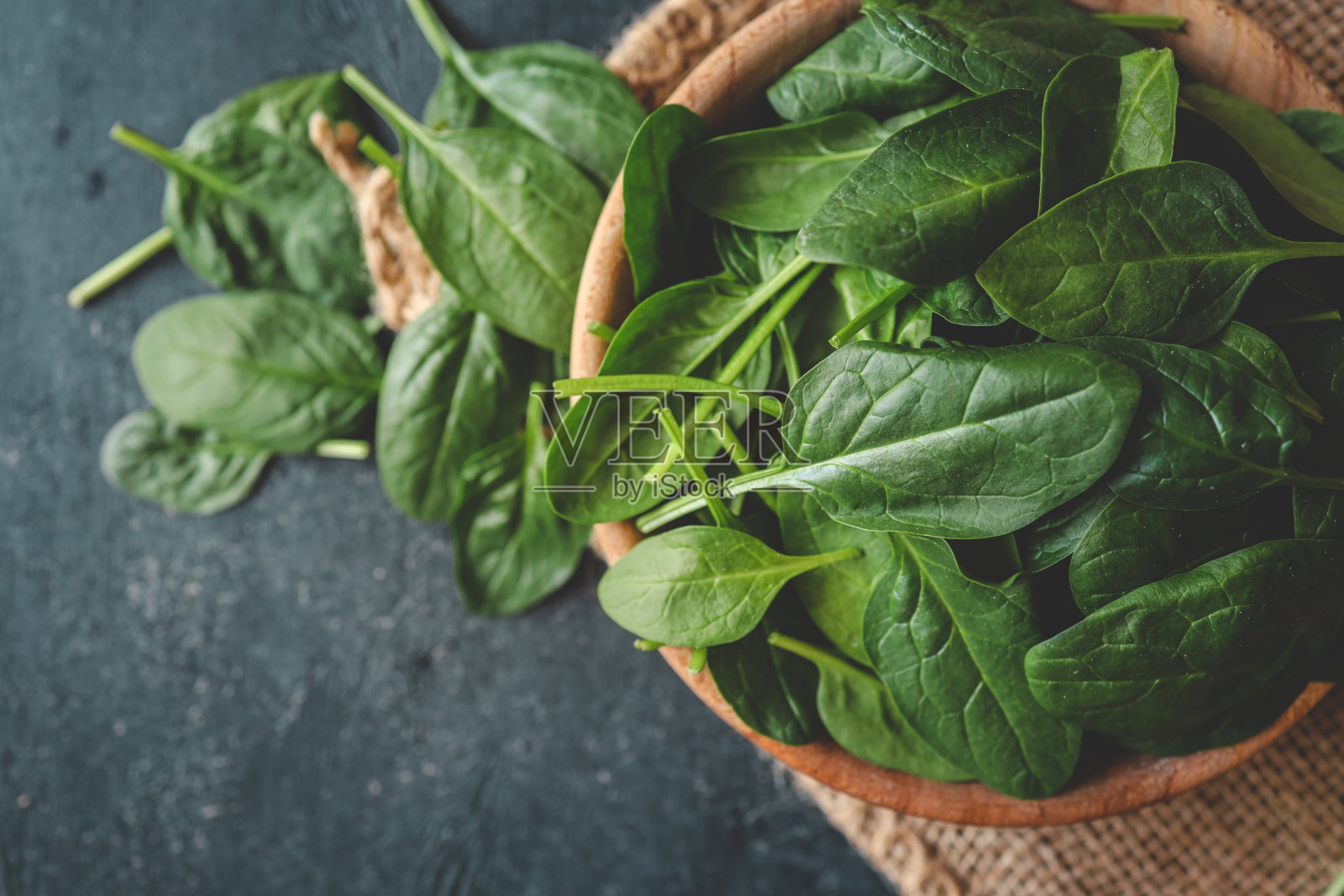 新鲜的有机菠菜叶在一个木制的碗在黑暗的乡村背景。带复制空间的俯视图照片摄影图片
