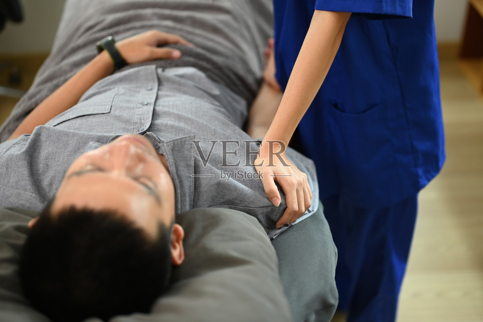 物理治疗师在诊所内检查男性病人的肩关节，并检查病人的活动能力。照片摄影图片