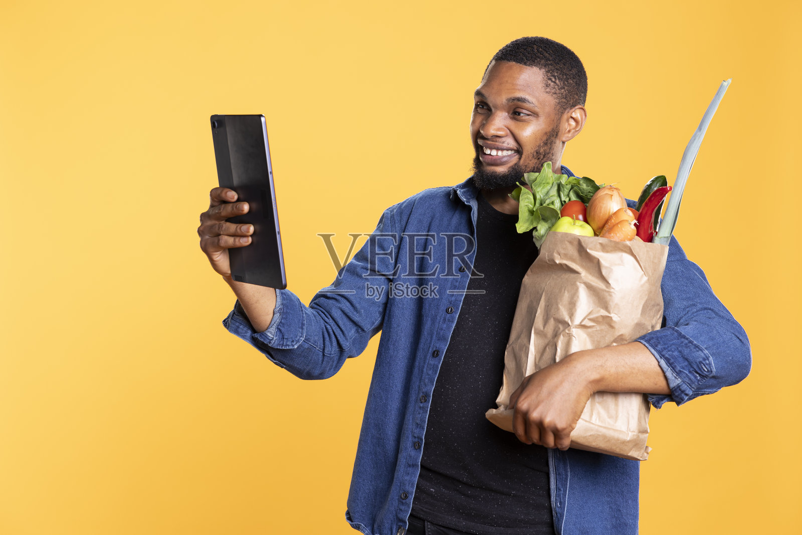 微笑的男模特在工作室用他的平板电脑查看社交照片摄影图片