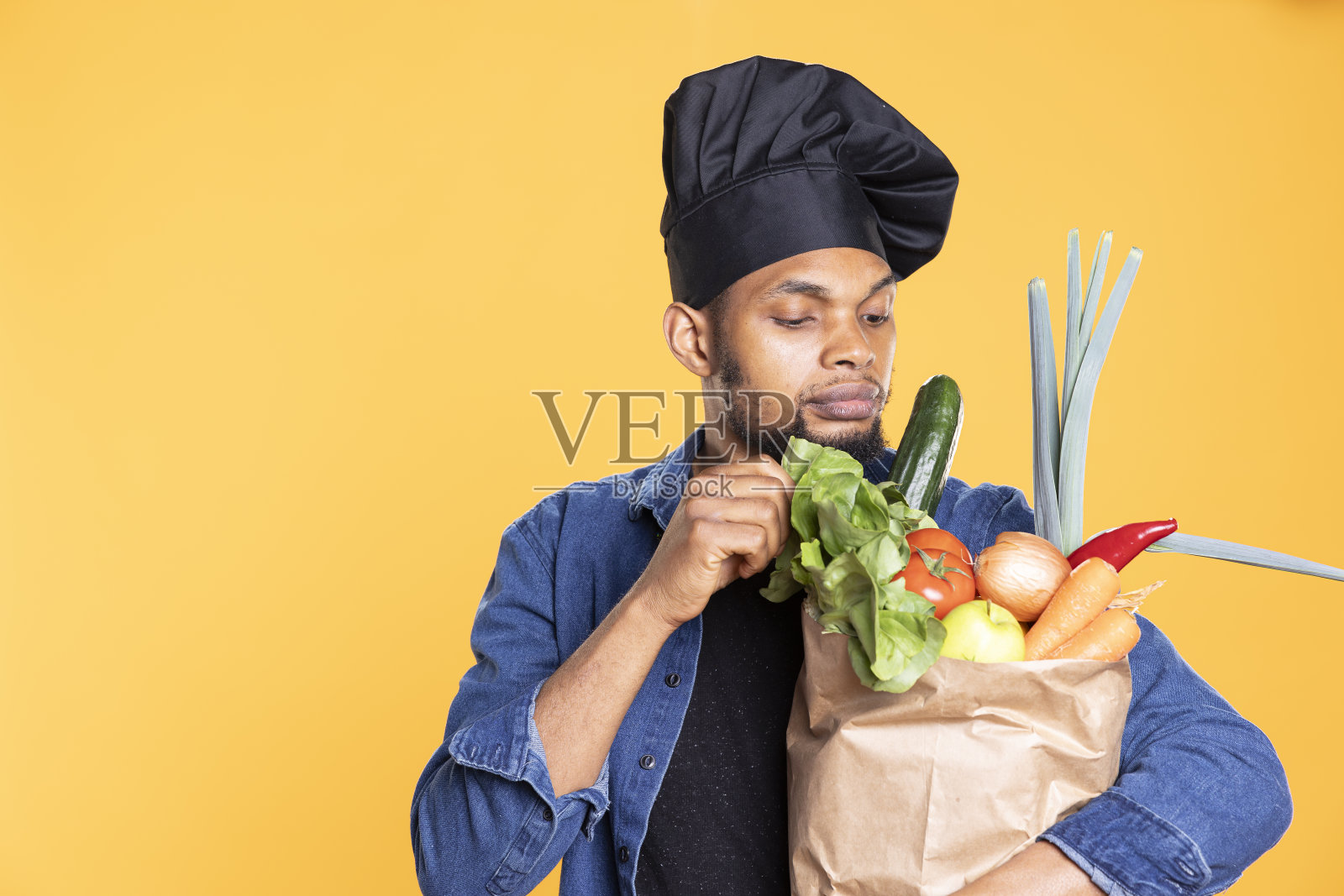 年轻的专业厨师闻着纸袋里新鲜的水果和蔬菜照片摄影图片