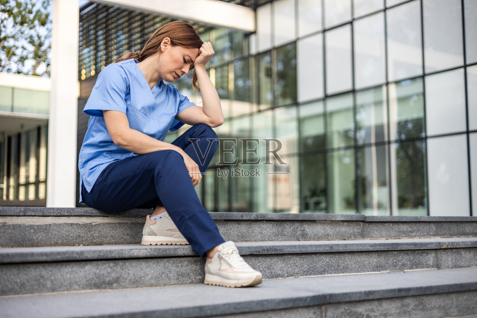 一名身穿制服的护士坐在医院外，显然很担心，专注于治疗病人照片摄影图片