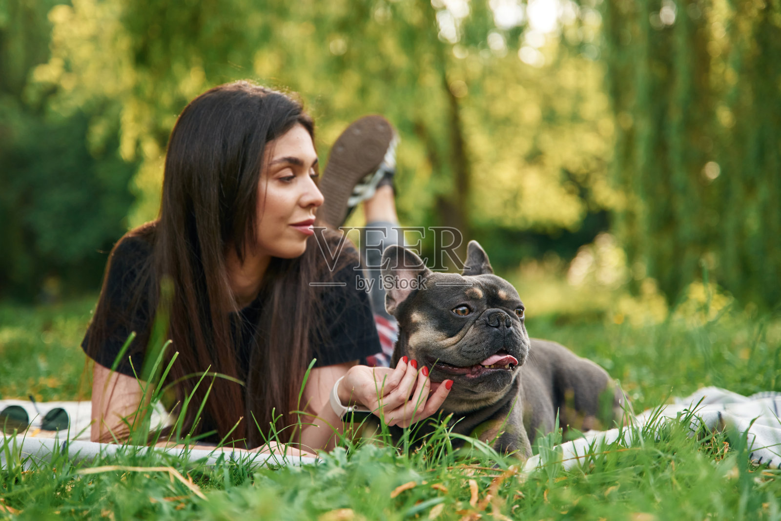 美丽的女人在户外。年轻漂亮的女人和她的狗在公园里照片摄影图片