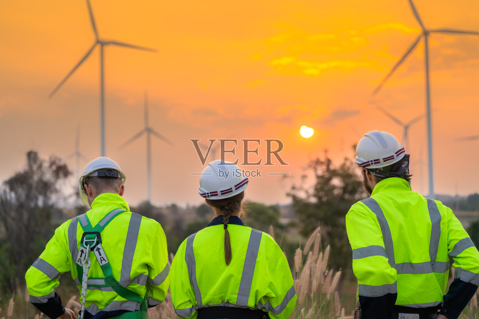 工程师们在夕阳的天空下检查和检查建筑。人操作。风力发电机是一种清洁能源和环境电力。工业的可持续发展。照片摄影图片