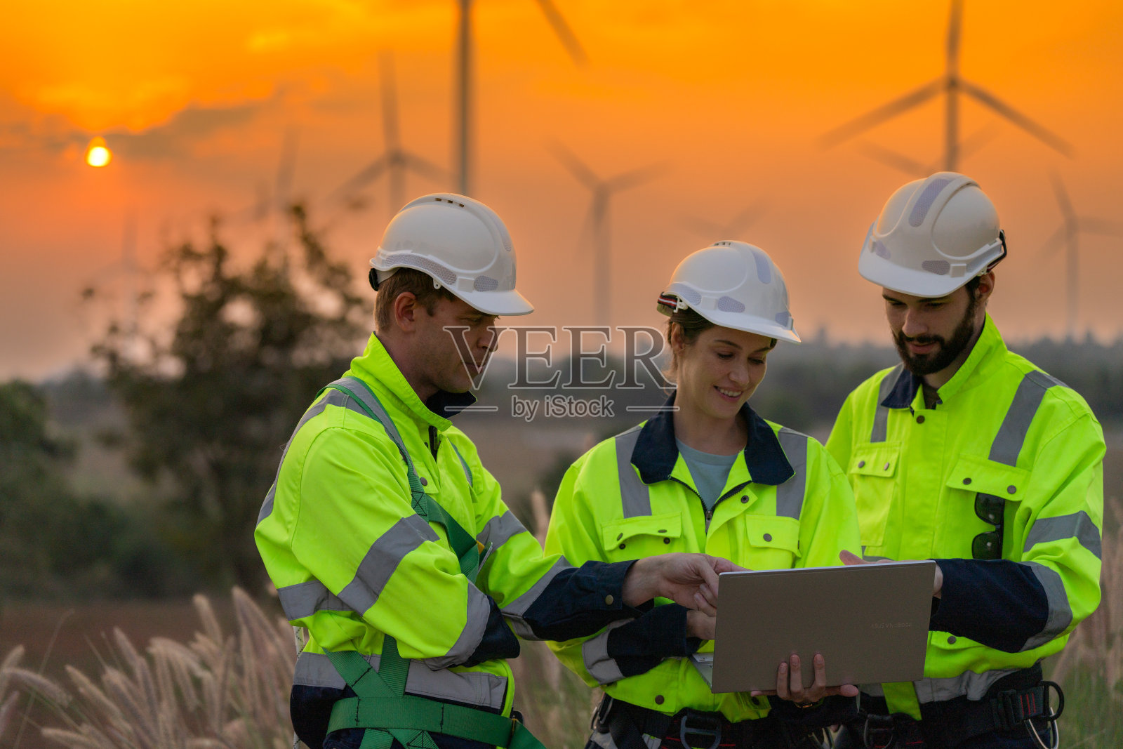 工程师们在夕阳的天空下检查和检查建筑。人操作。风力发电机是一种清洁能源和环境电力。工业的可持续发展。照片摄影图片