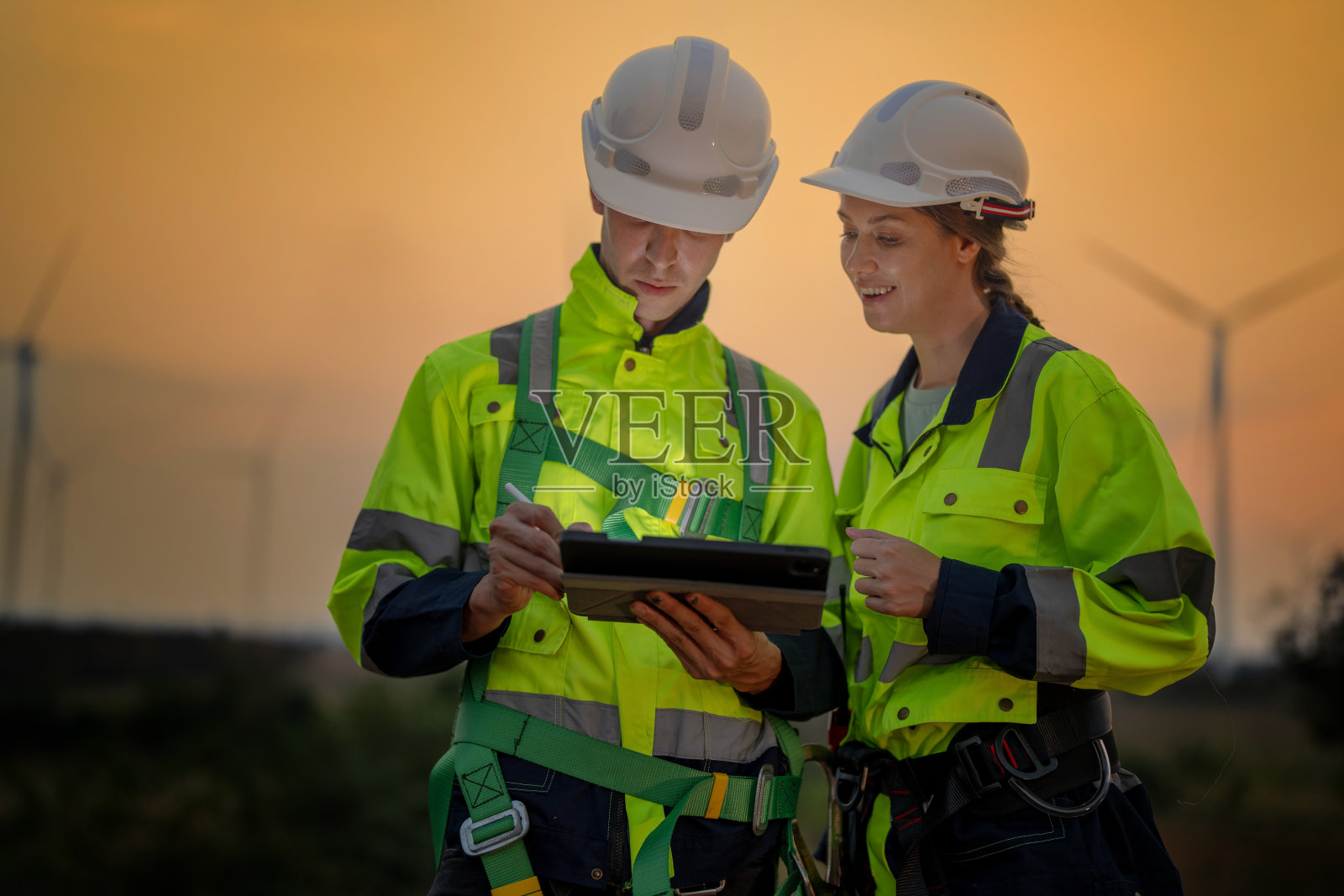 工程师们在夕阳的天空下检查和检查建筑。人操作。风力发电机是一种清洁能源和环境电力。工业的可持续发展。照片摄影图片