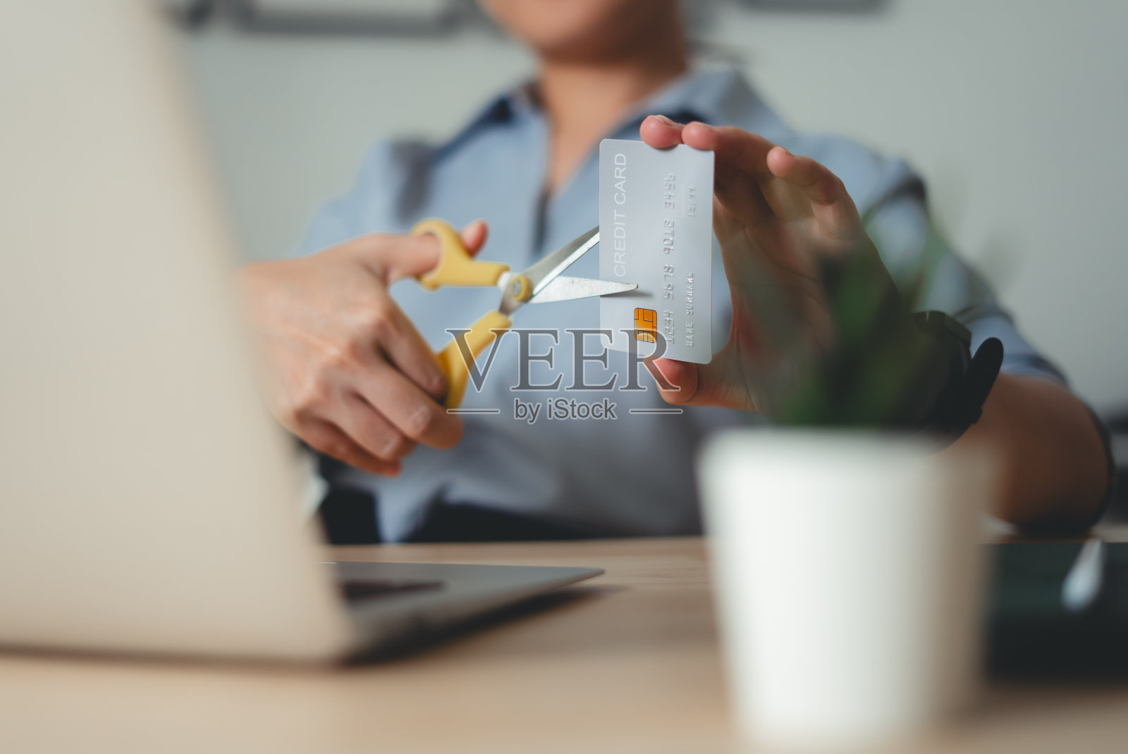 家庭办公室桌子上女性用剪刀剪信用卡的特写镜头。照片摄影图片