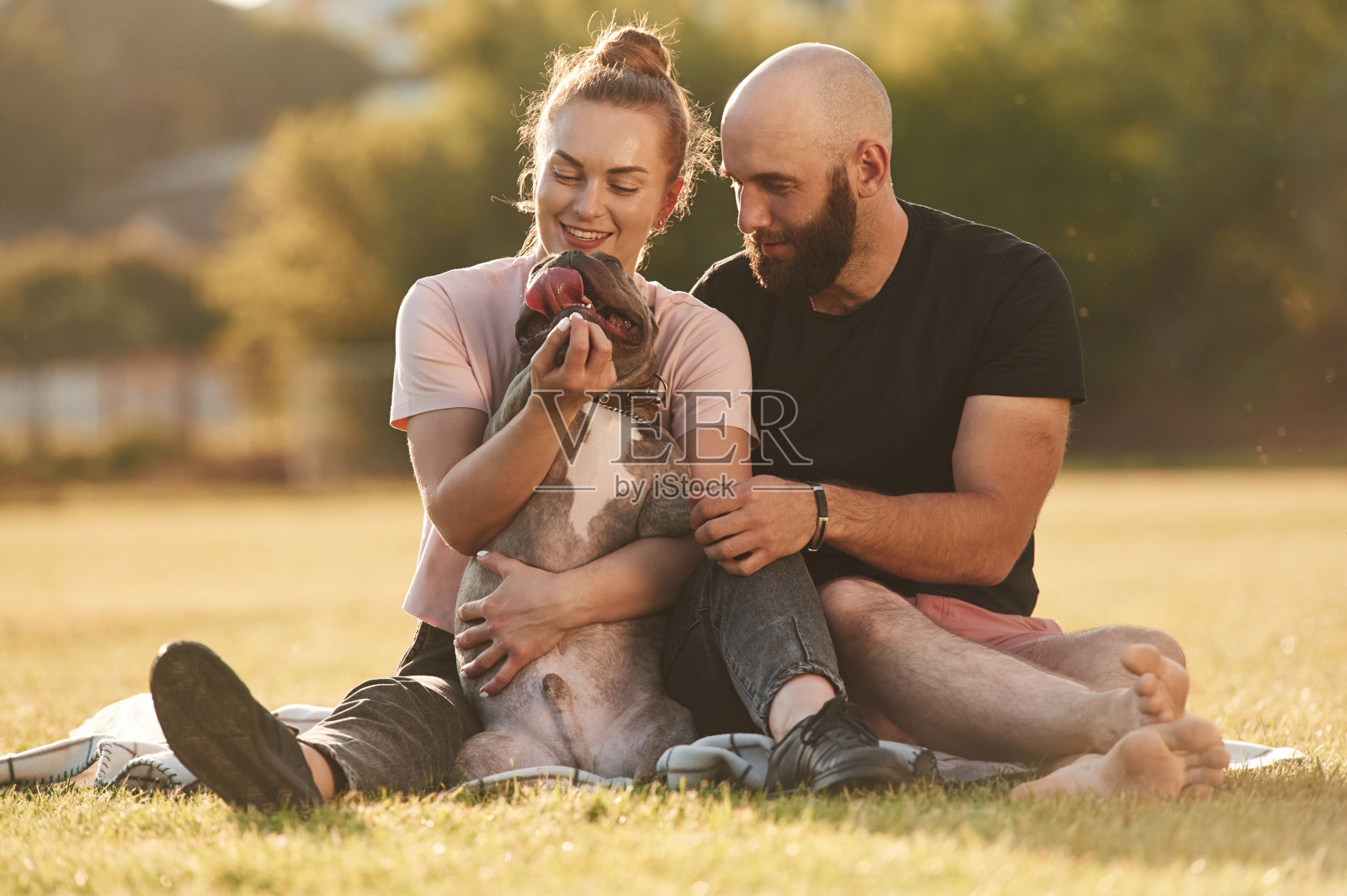 休息一下，坐着。一男一女带着狗在操场上照片摄影图片