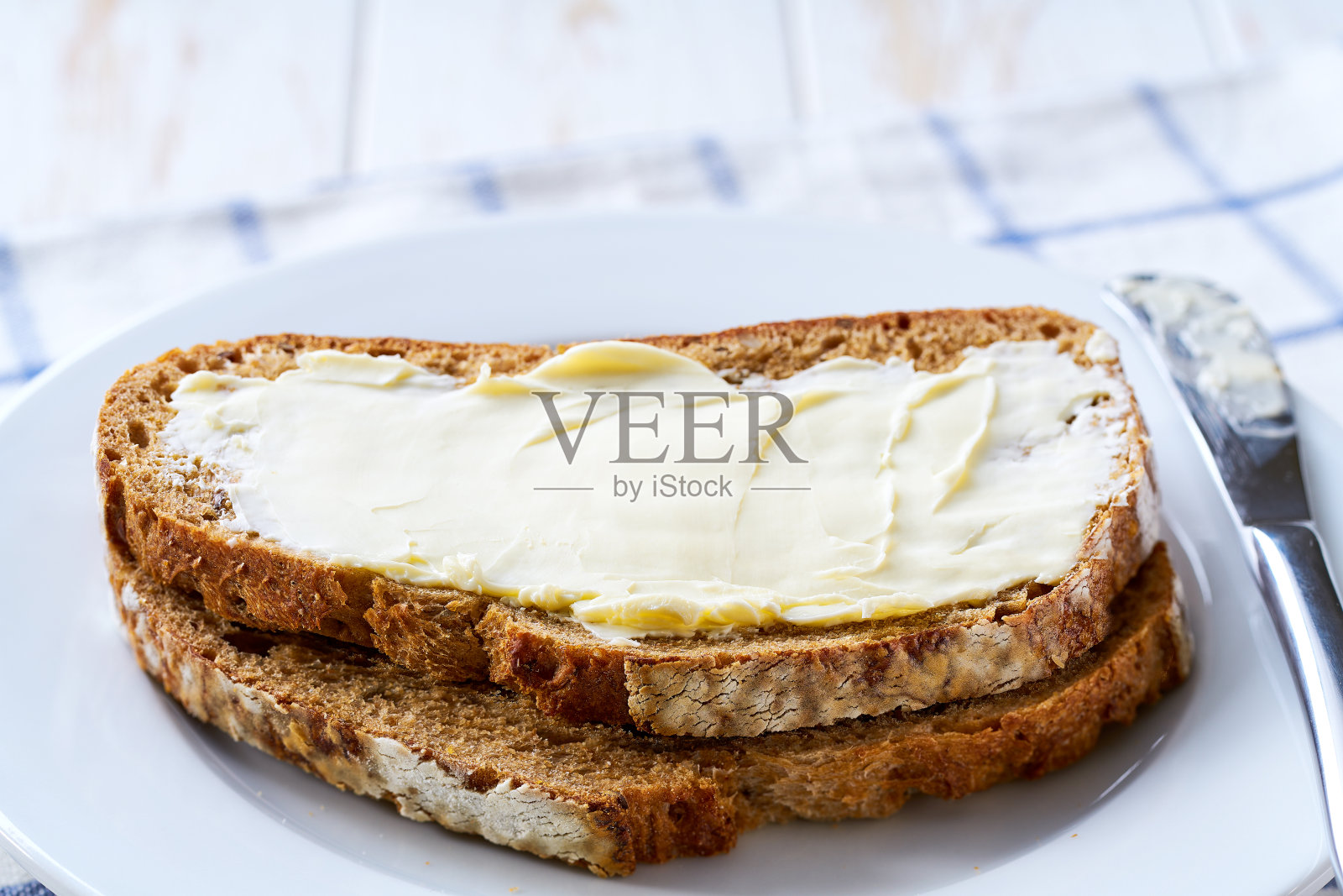 几片涂了黄油的黑麦面包，放在餐桌上。照片摄影图片