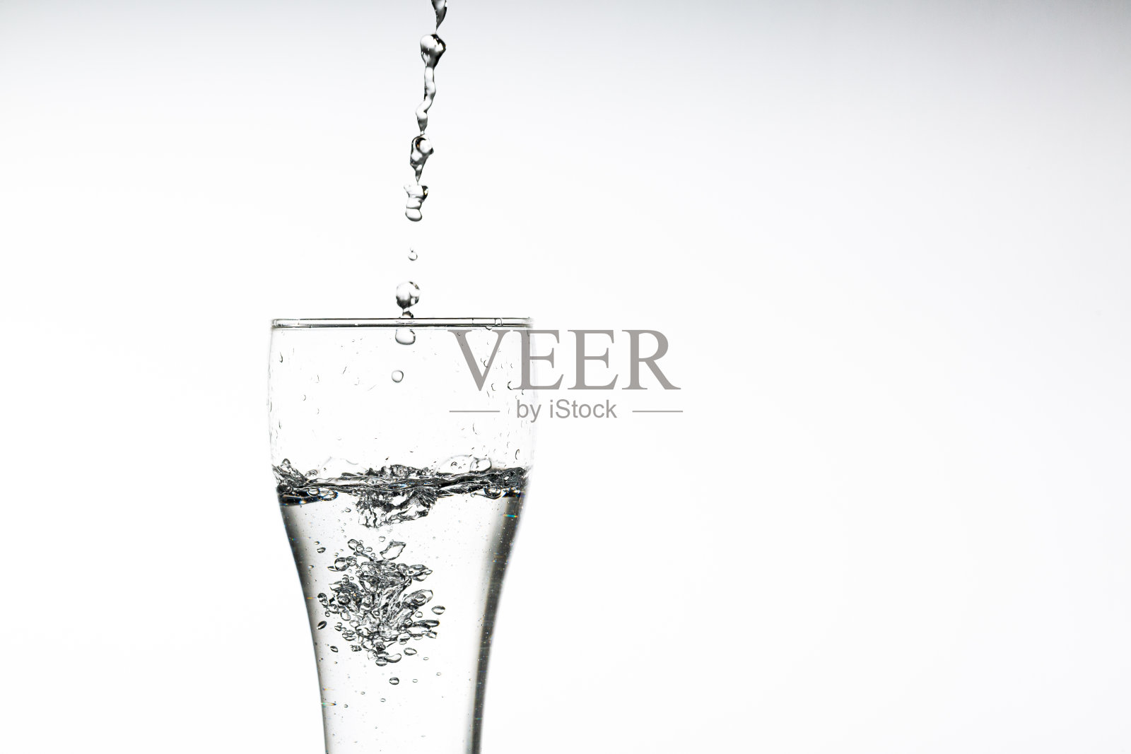 把水倒进白色背景的杯子里。特写图片，白色背景上的一杯饮用水，照片摄影图片