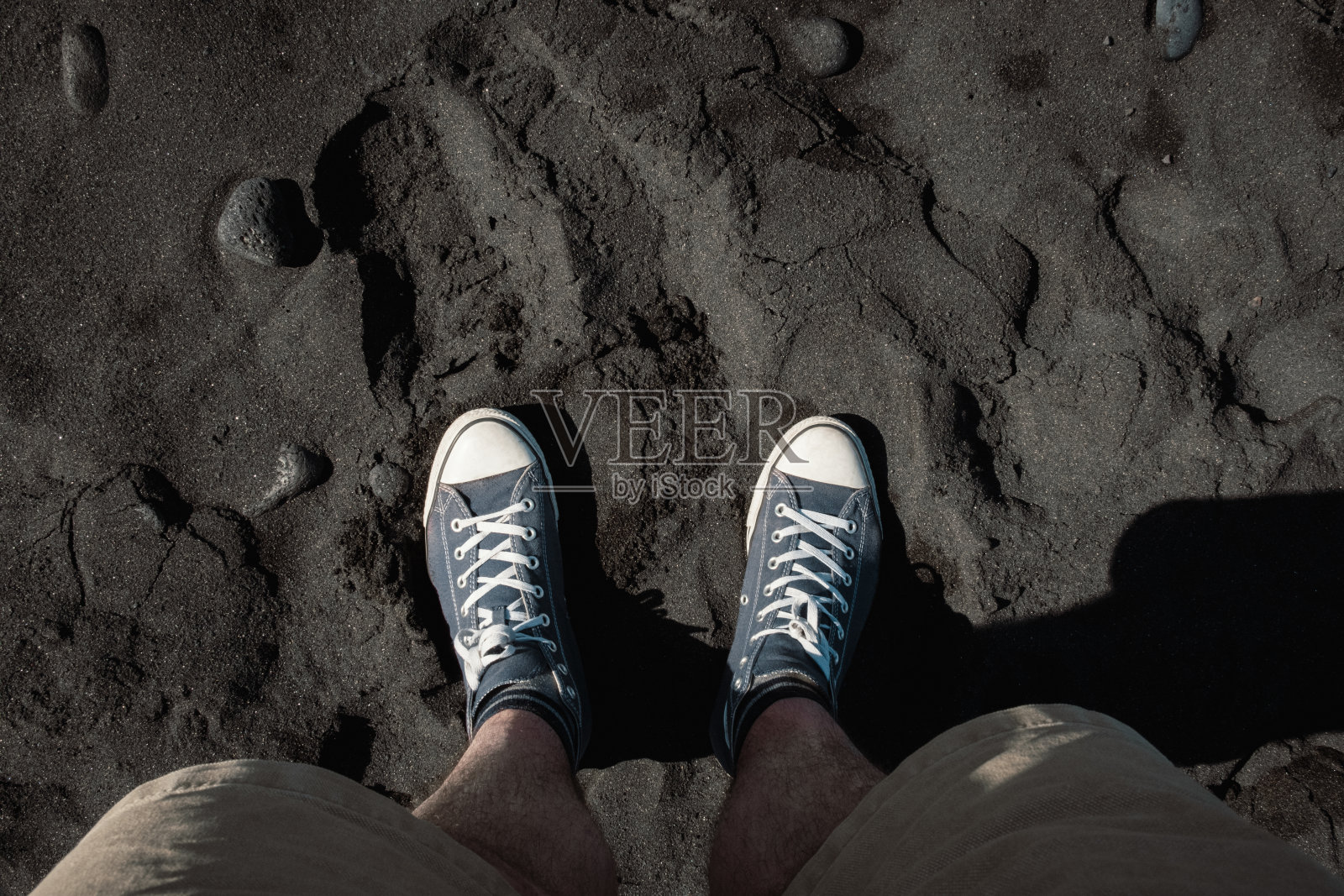 俯瞰在西班牙加那利群岛特内里费岛黑色沙滩上行走的男人的鞋子照片摄影图片