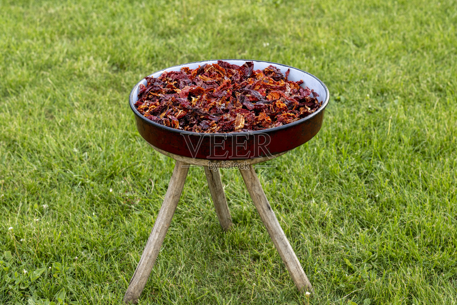 用红干辣椒做的红砂锅，展现了香料的质地和概念。平底锅放在一个有三条腿的木凳上。照片摄影图片