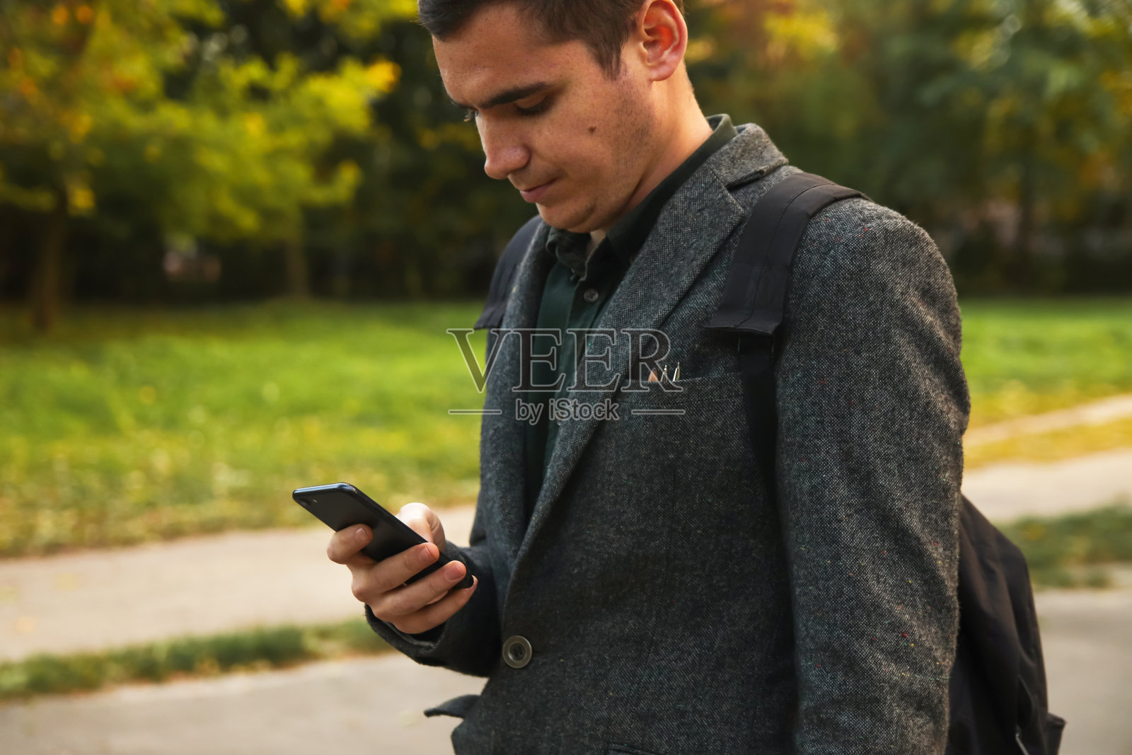 夏天在户外使用手机的年轻商人，科技与自然。夏天，穿着商务装的男子在户外使用智能手机，自然背景照片摄影图片