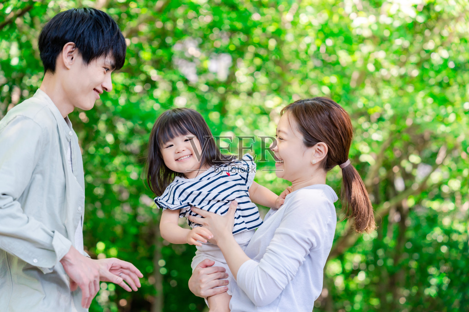 一家人抱着穿着绿色衣服的孩子照片摄影图片