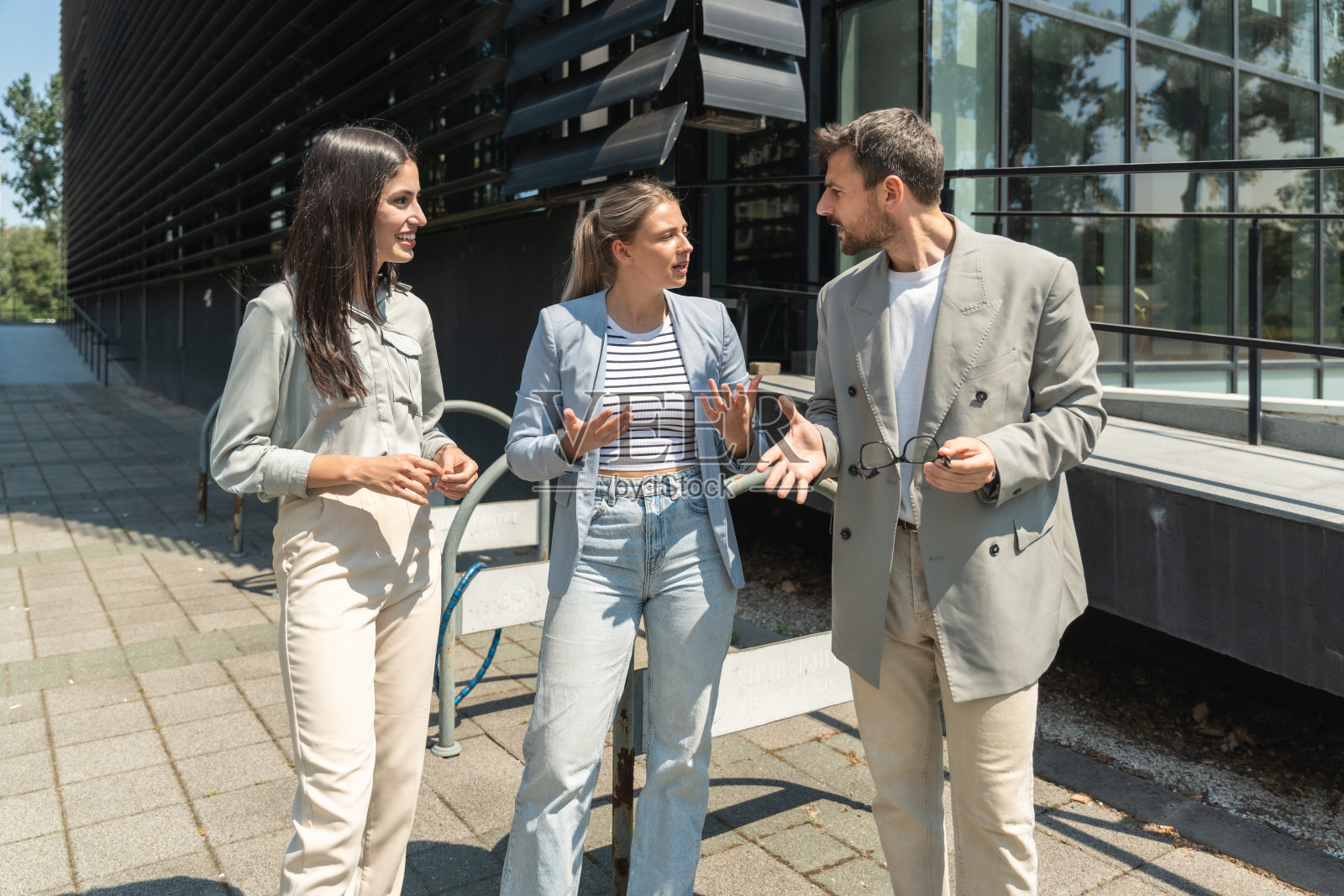 一群年轻的成功商人，商人和女商人穿着正装站在办公大楼外，讨论着生意。酷快乐的外籍公司专家交流信息照片摄影图片