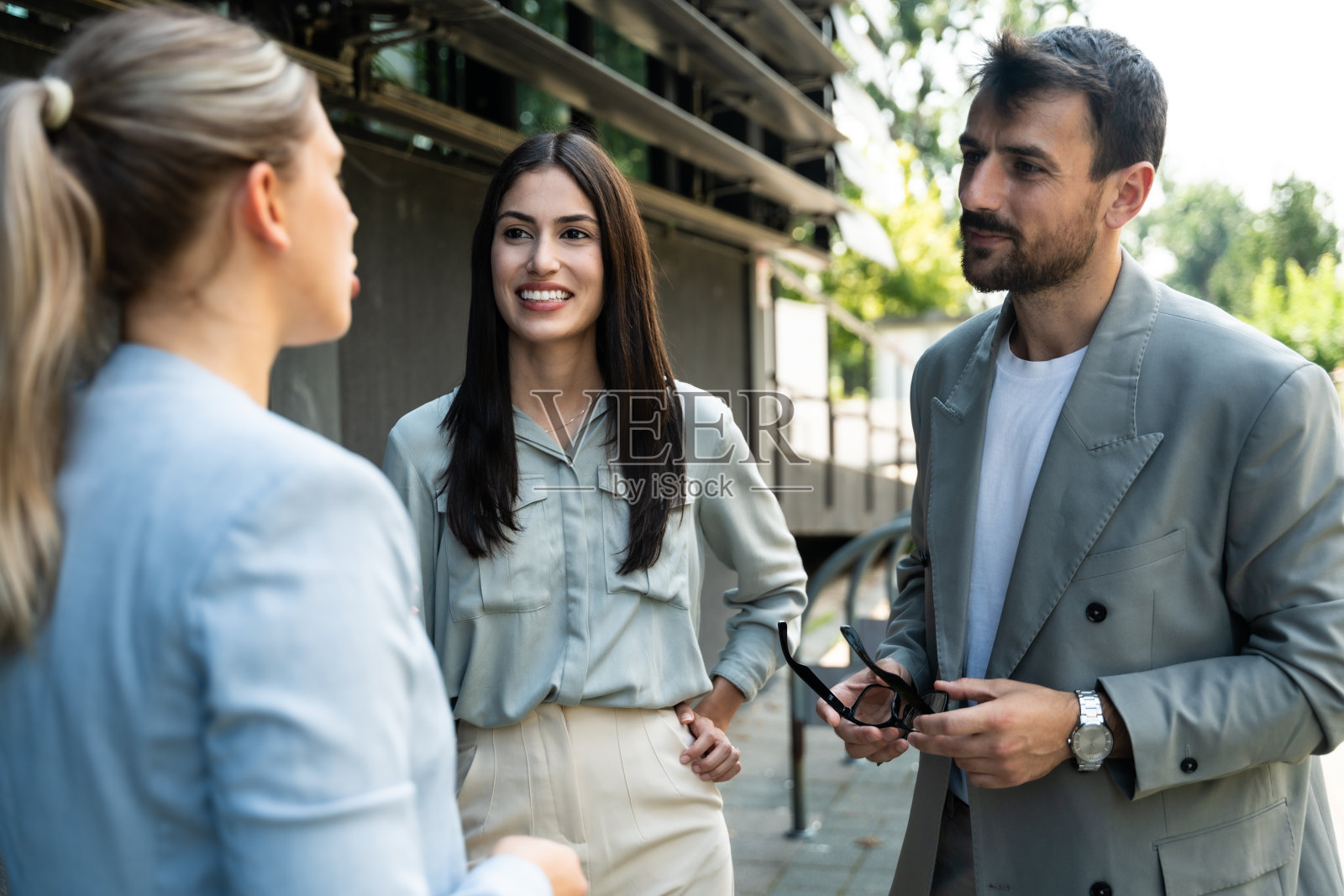 一群年轻的成功商人，商人和女商人穿着正装站在办公大楼外，讨论着生意。酷快乐的外籍公司专家交流信息照片摄影图片