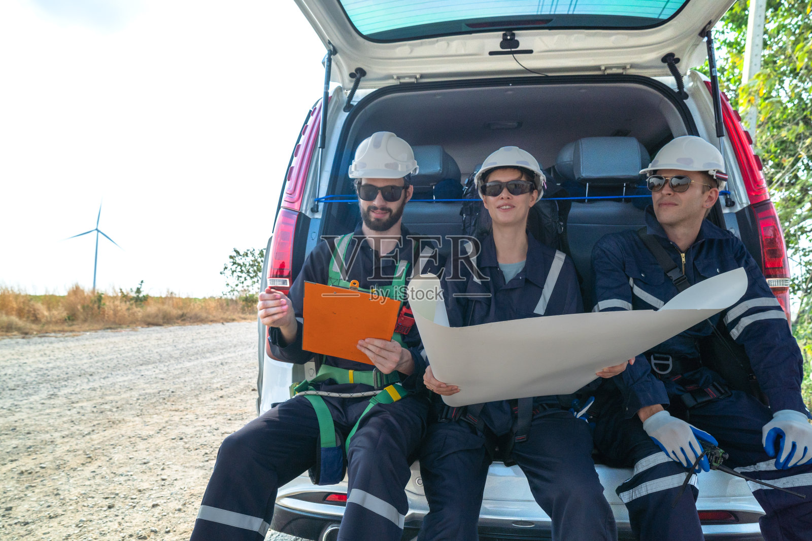 图为，为了生产清洁电力，在偏远地区，一群工程师坐在一辆面包车里，正在检查风力涡轮机和周围设施的施工情况。照片摄影图片