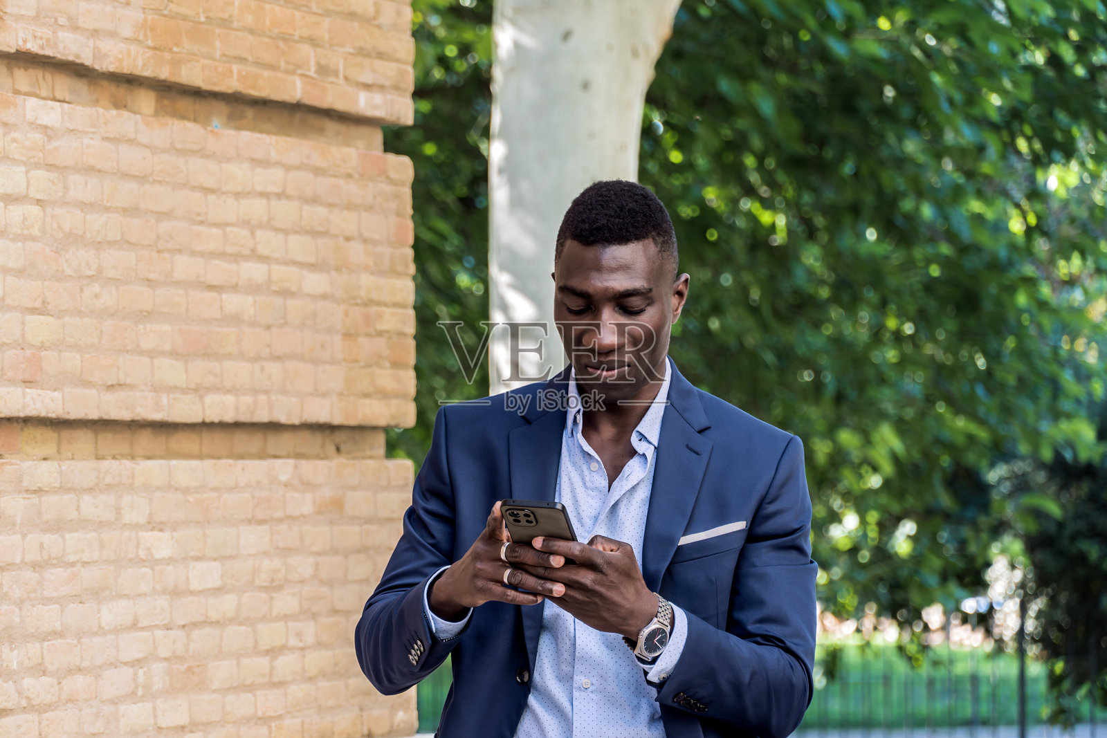 年轻的黑人行政人员微笑着用智能手机做手势，文本区域照片摄影图片