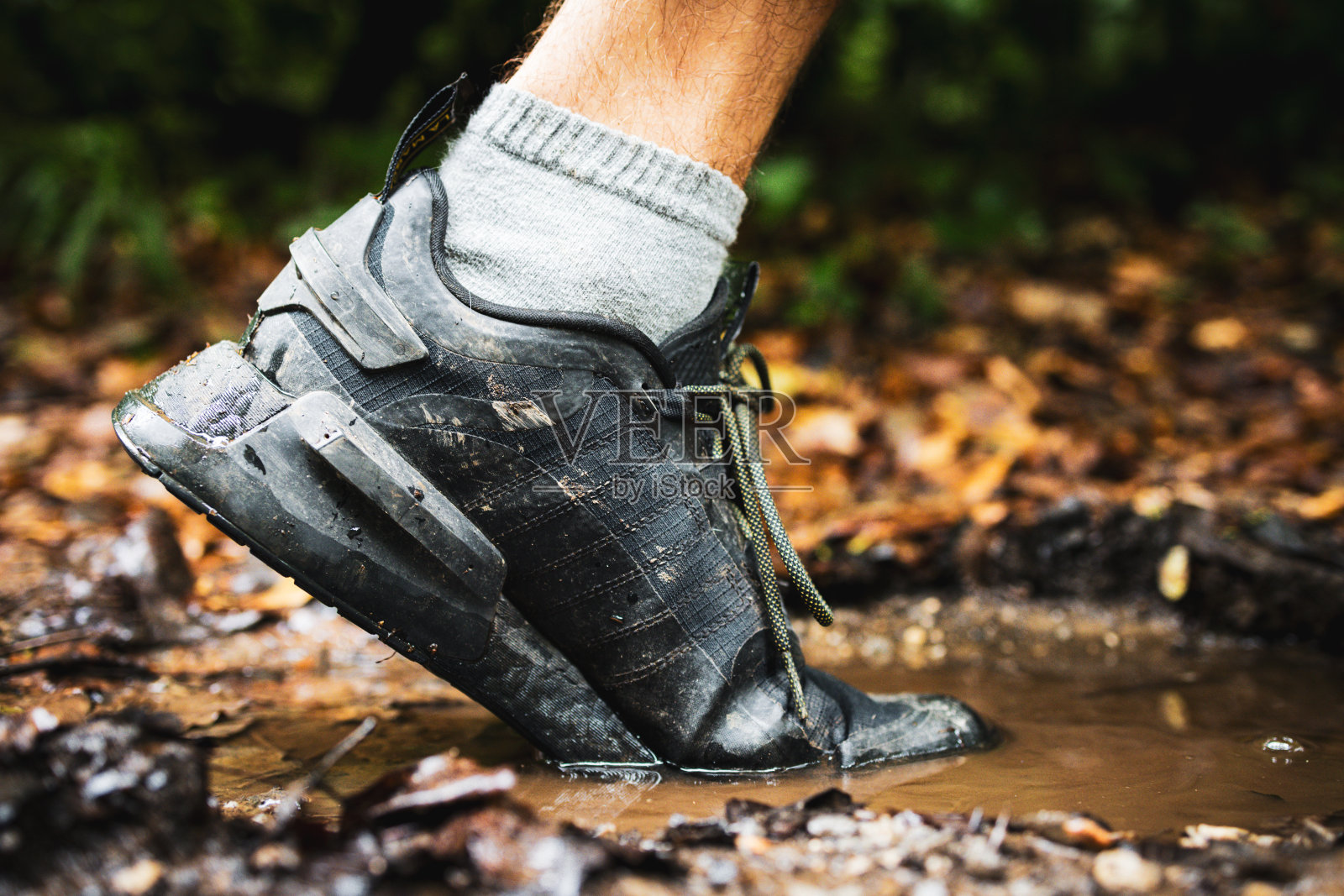 近距离拍摄的跑步鞋踩进泥泞的小路照片摄影图片