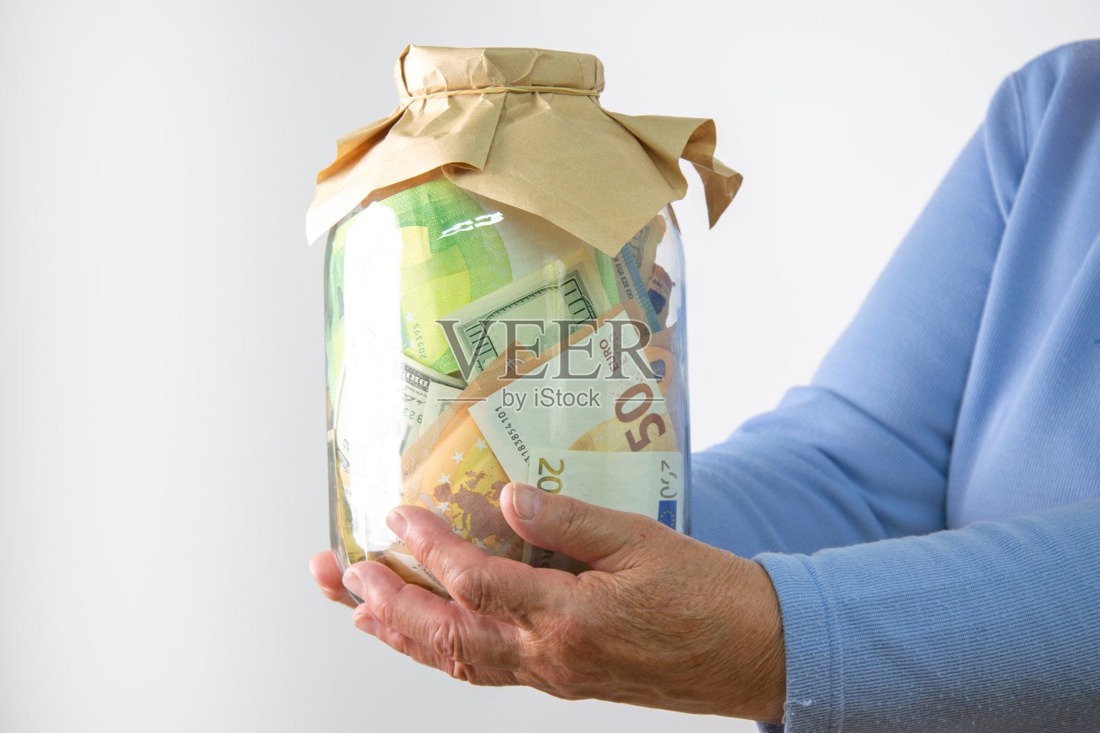 一个人的手拿着一个装满美元和欧元钞票的玻璃罐照片摄影图片