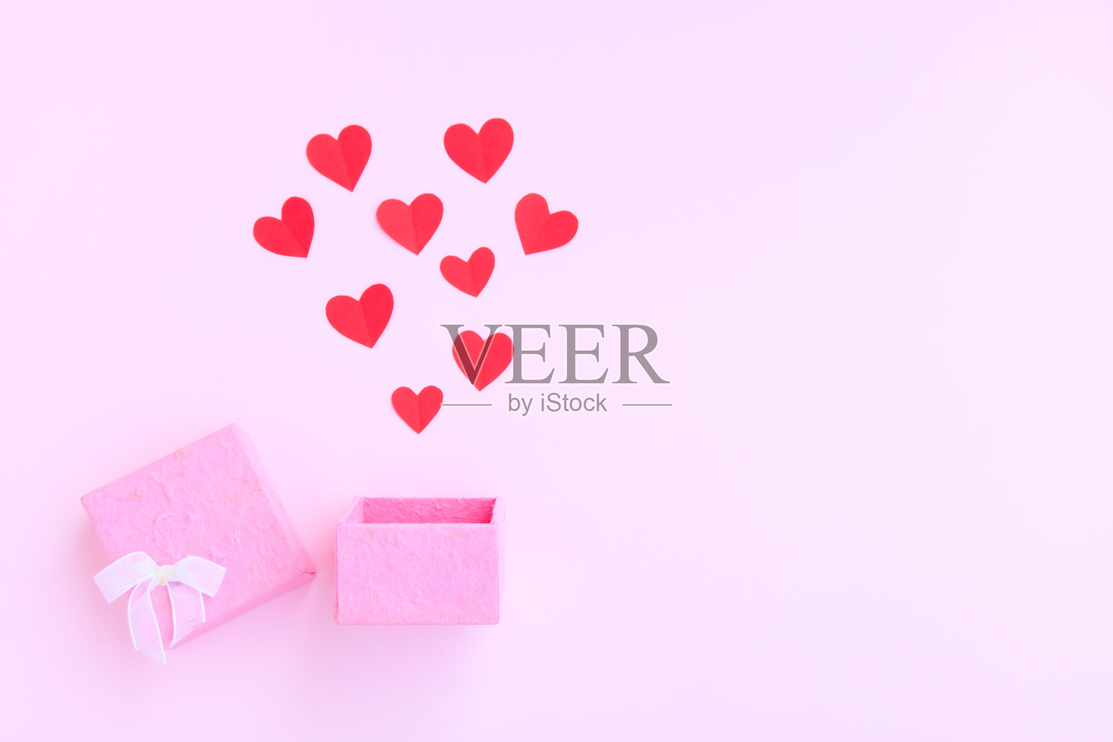 粉红色礼盒与红纸心在粉红色的背景，手工纸盒和剪纸照片摄影图片