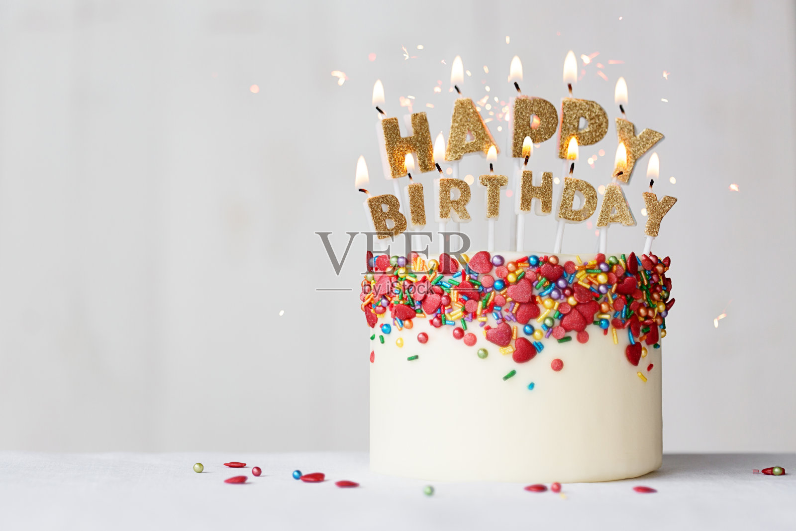 生日快乐蛋糕，配上金色的蜡烛和心形的糖屑照片摄影图片