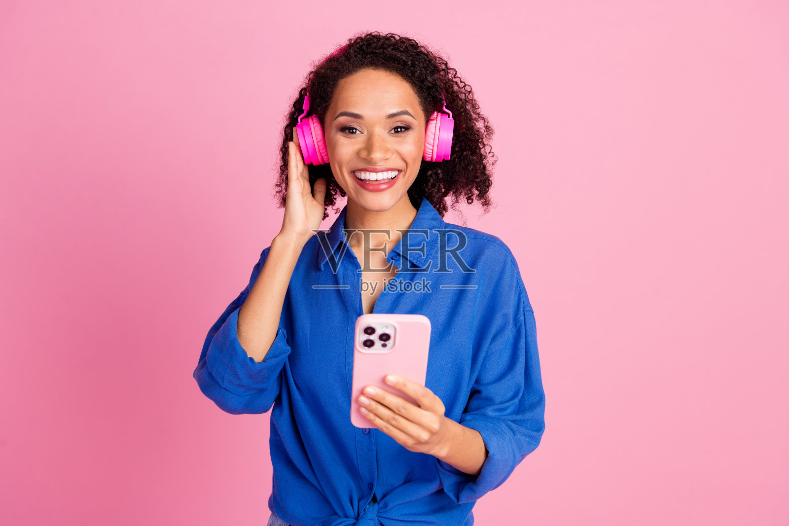 开朗可爱可爱的女人穿着时髦的衣服听音乐无线耳机孤立在粉红色的背景照片照片摄影图片