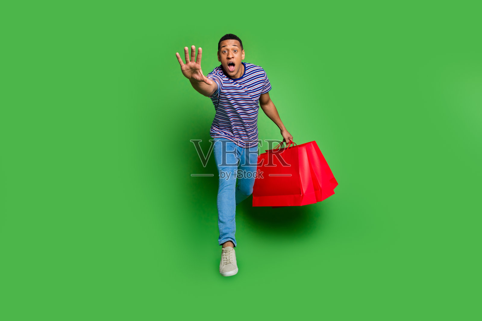 漂亮的年轻人的全身肖像跳跑商店袋穿t恤孤立的绿色背景照片摄影图片