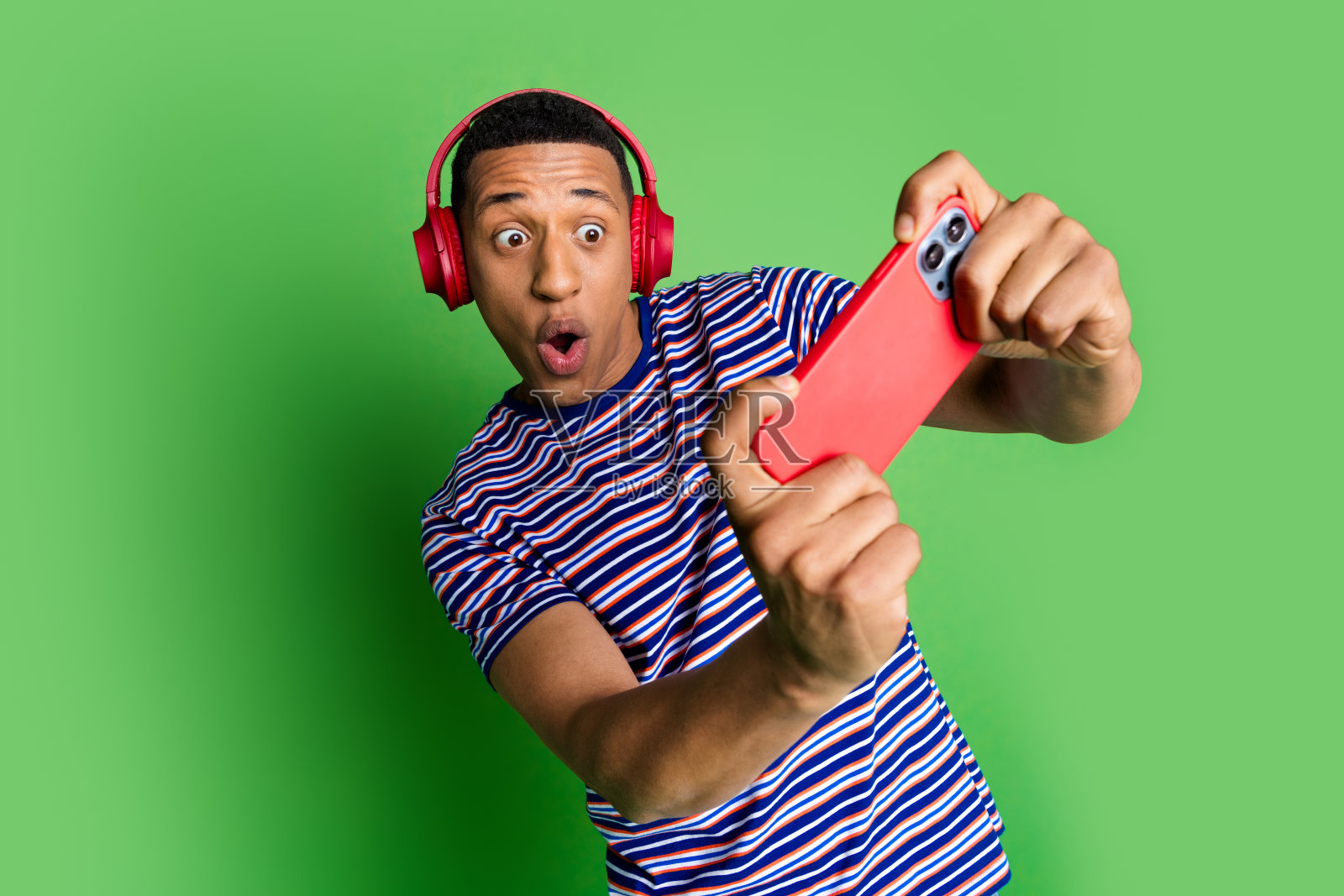 疯狂酷男人的照片，穿着条纹时尚的衣服，在绿色的背景上孤立地玩游戏照片摄影图片